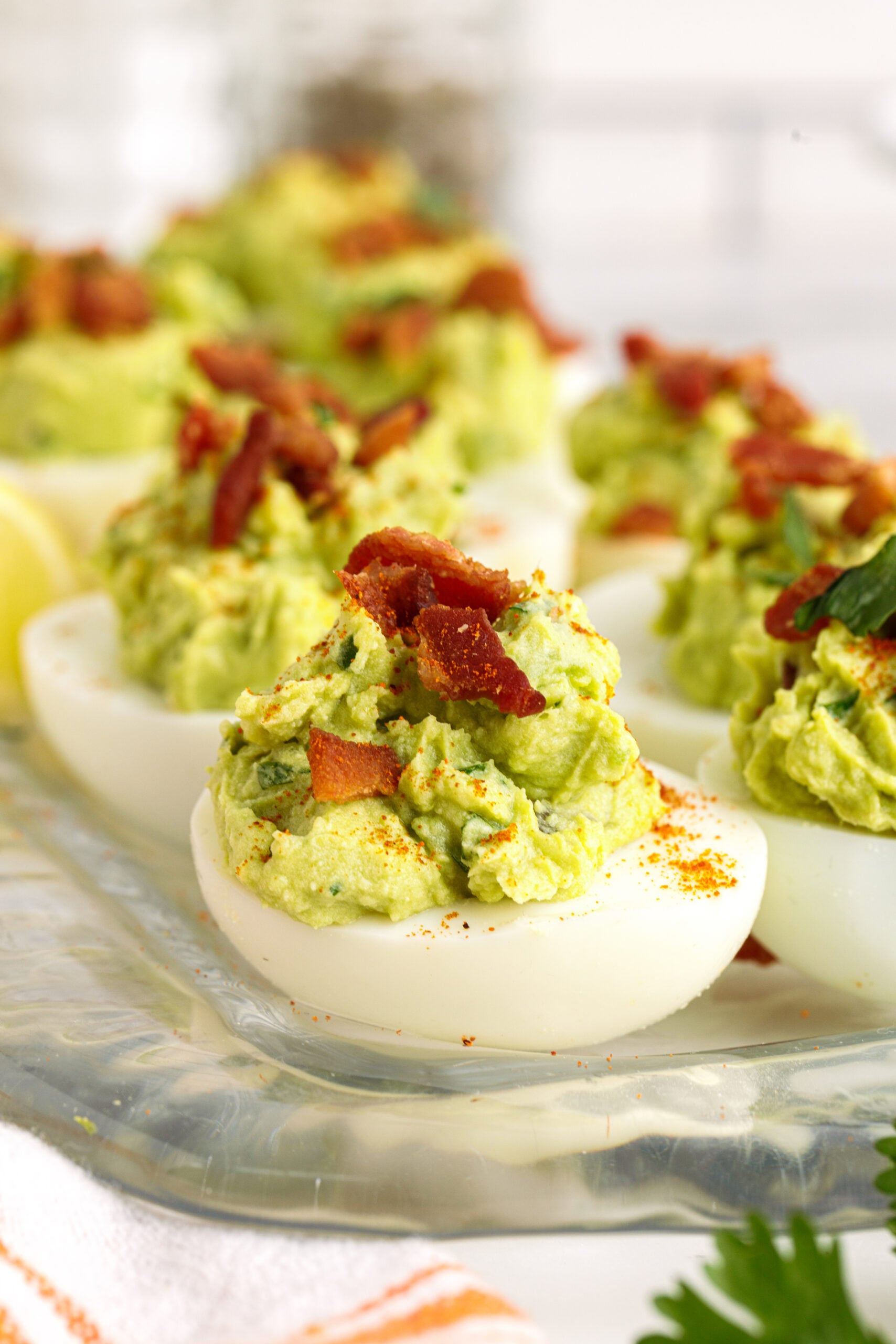 Side view of Avocado Deviled Eggs topped with chopped bacon.