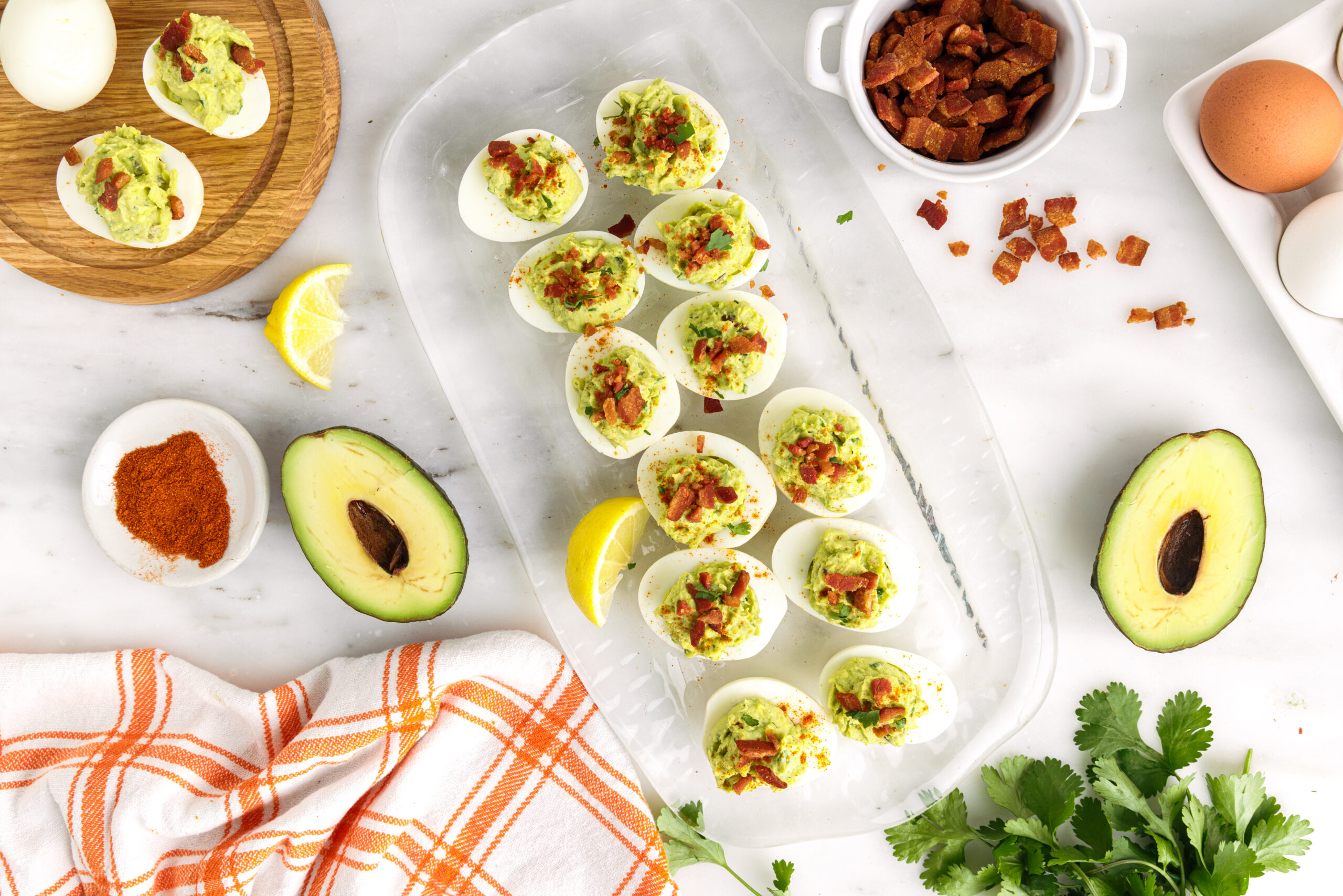 Overhead shot of one dozen avocado deviled eggs on a clear serving tray.