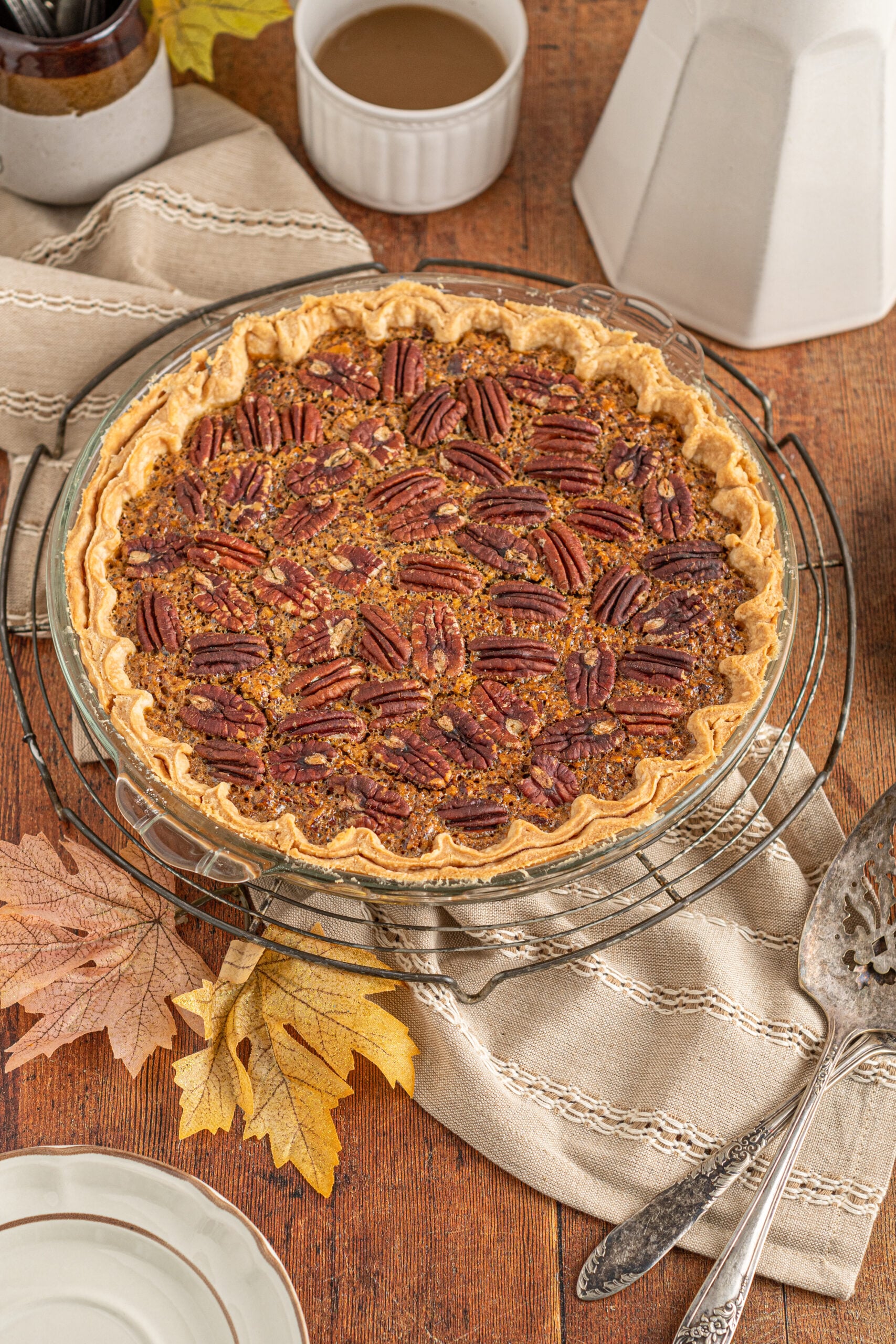 An overhead view of the pecan pie in a glass pie dish cooling on a wire rack.