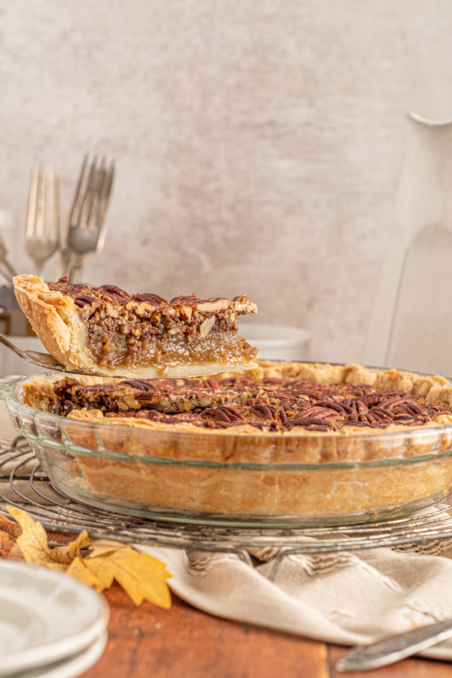 A side view of a piece of Bourbon Pecan Pie being removed from a glass pie dish.