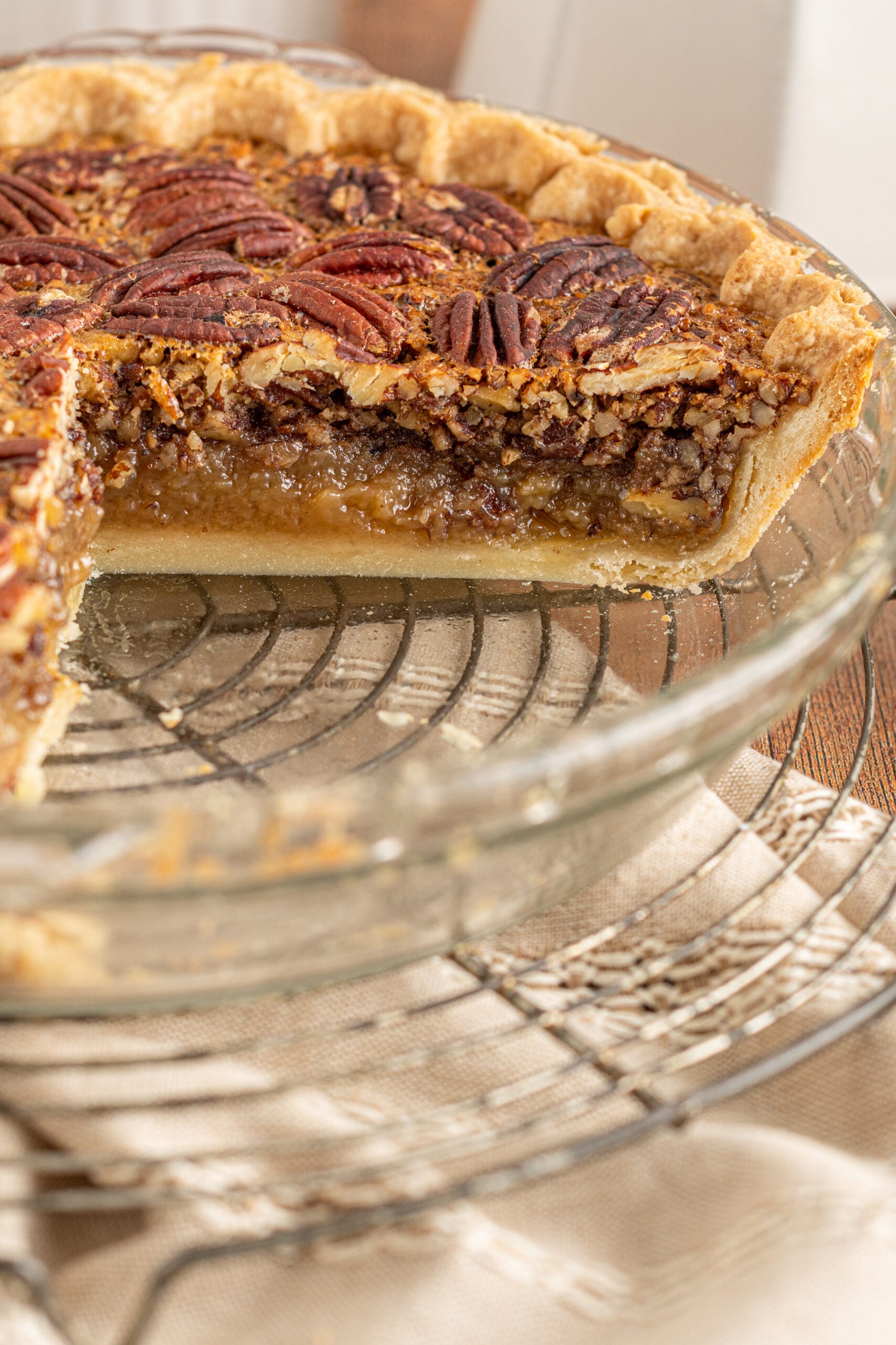 A center cut of the pecan pie in a glass pie dish.
