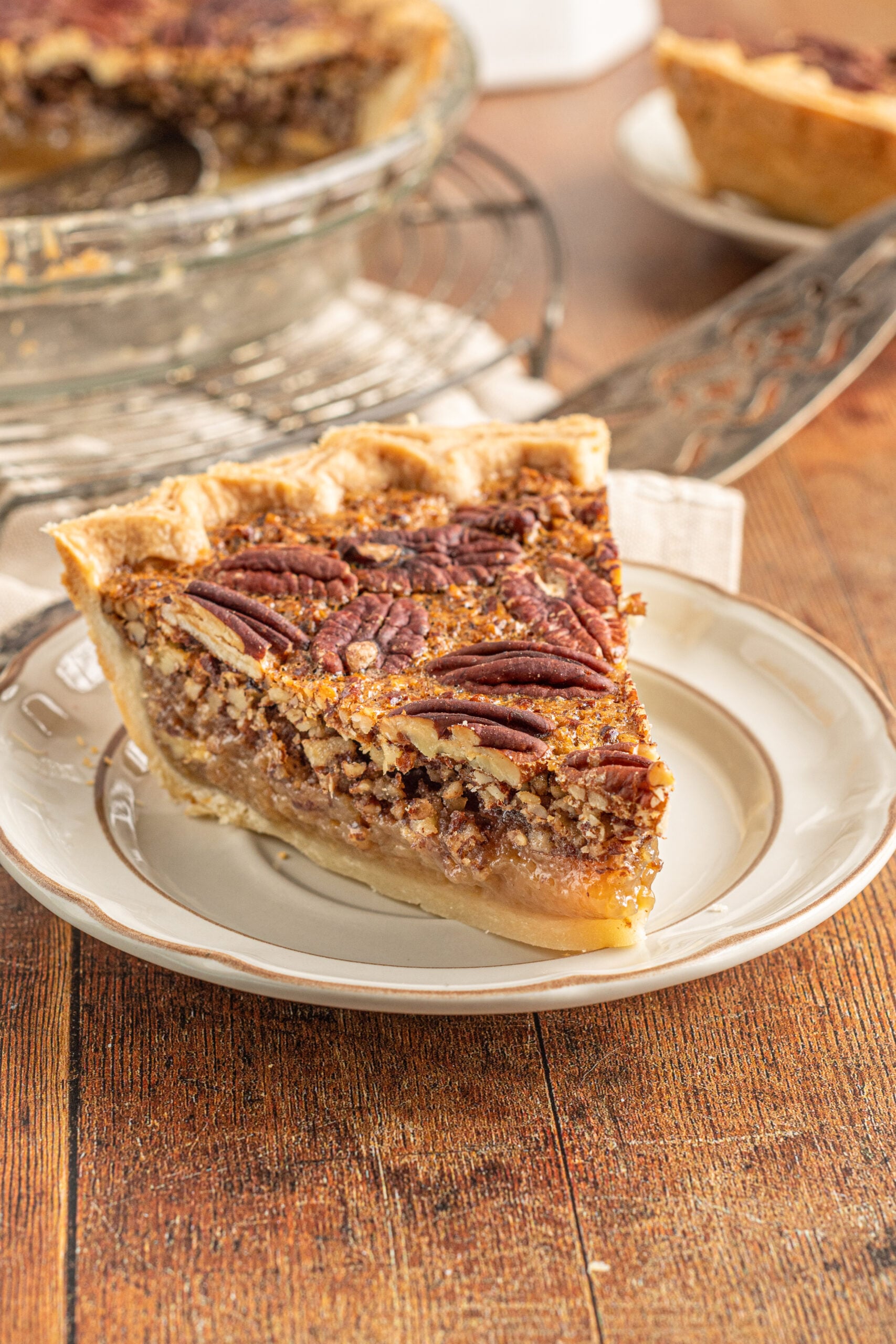 A piece of pecan pie on a tan and brown plate.