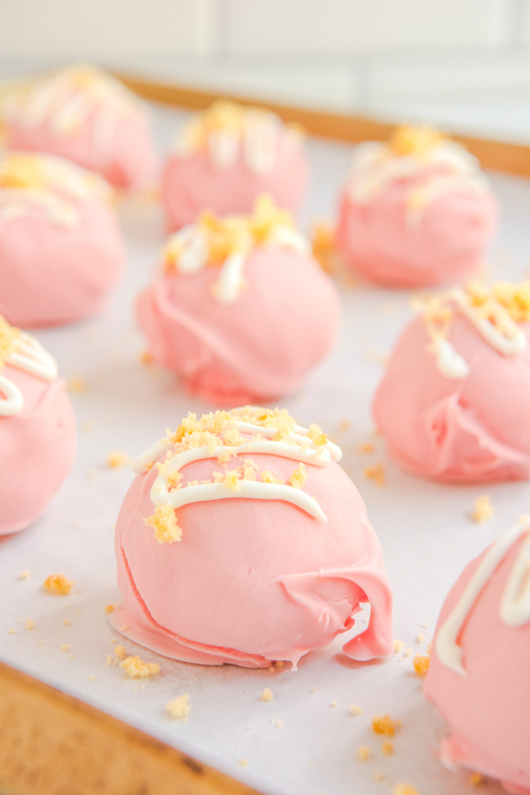 Strawberry Truffles on a baking tray with white chocolate drizzle topping. 