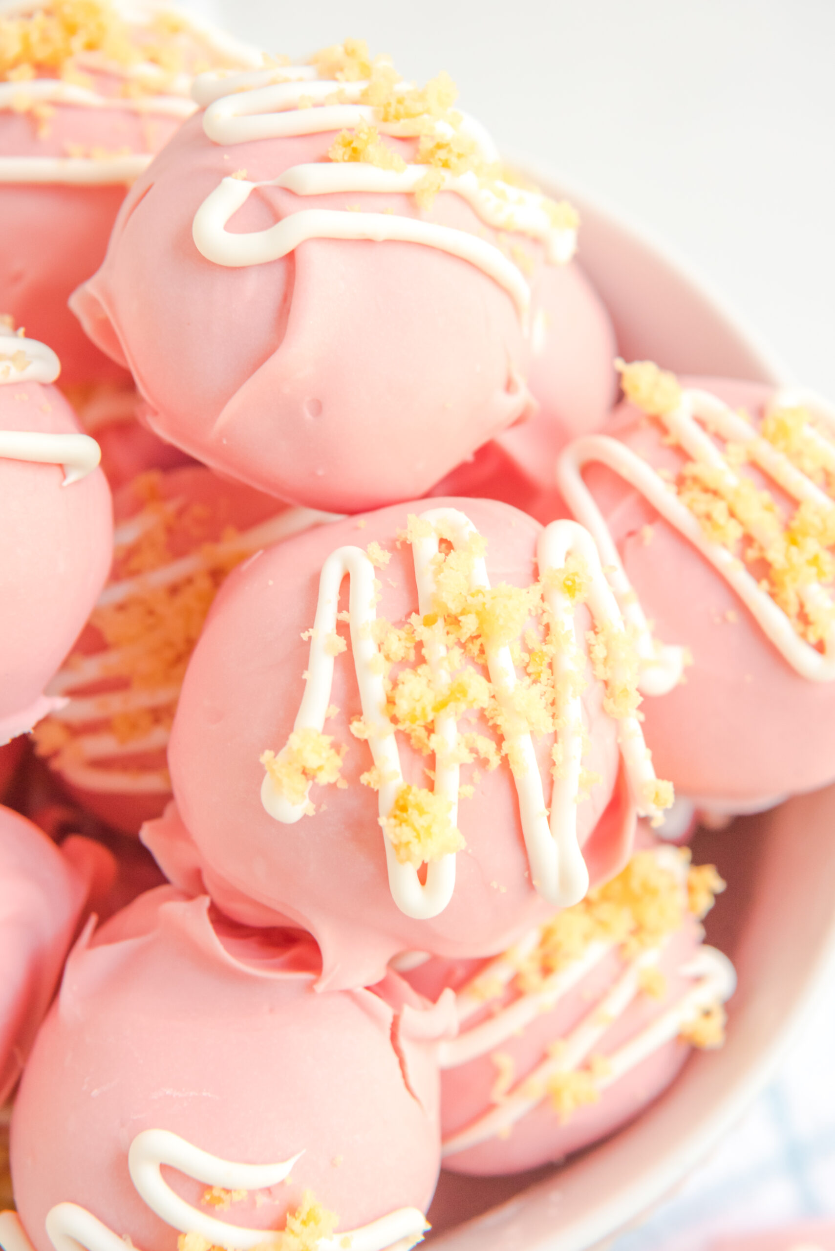Strawberry truffles stacked on top of each other in a white bowl. 
