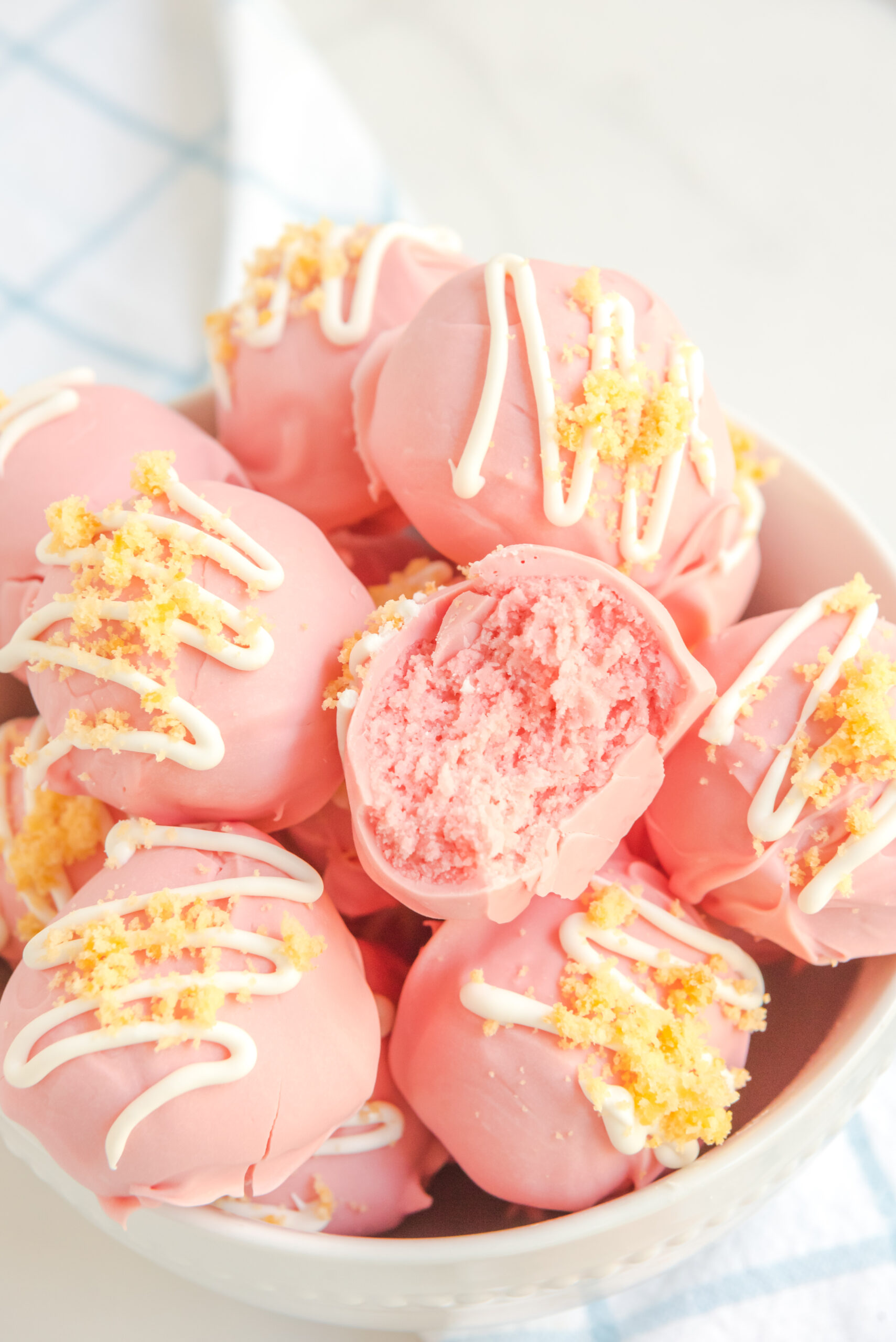 Strawberry truffles stacked on top of each other in a white bowl. 