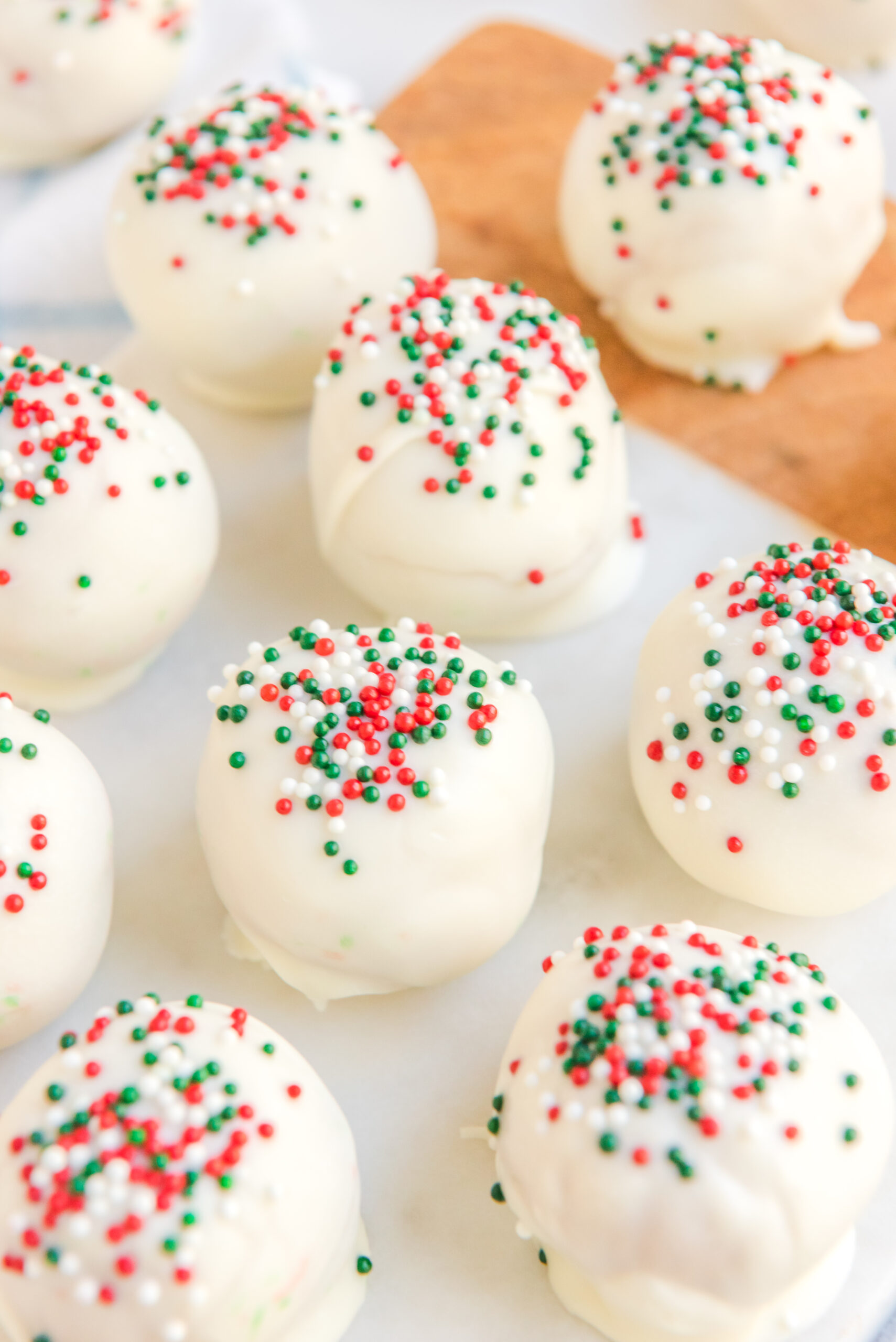 Close up of white chocolate peanut butter truffles topped with red, white, and green sprinkles. 