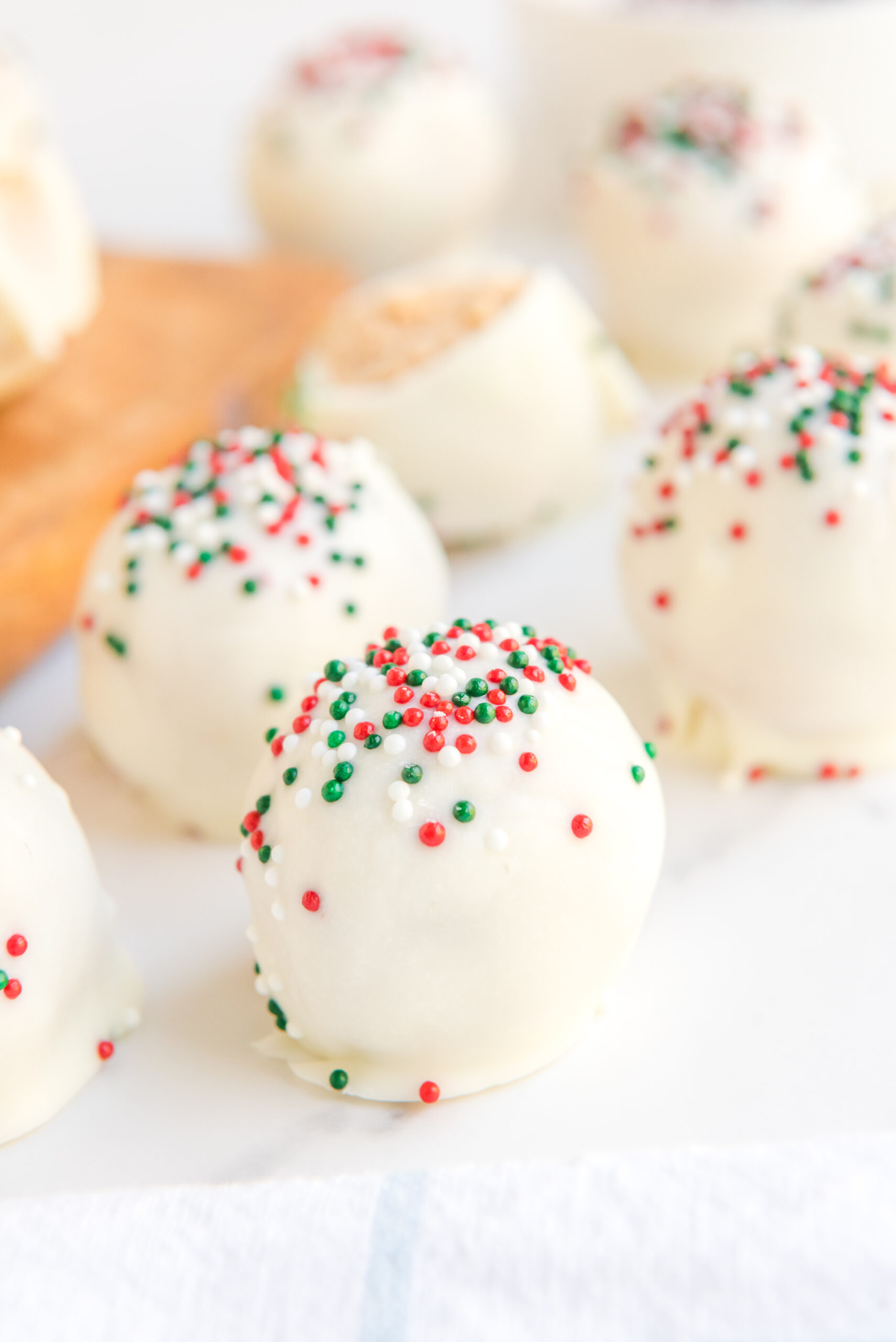 Close up of white chocolate peanut butter truffles topped with red, white, and green sprinkles. 