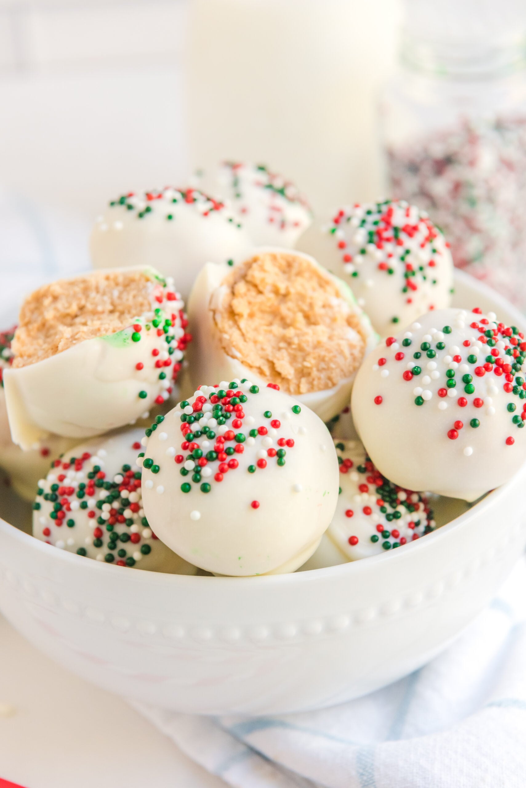 A White Chocolate Peanut Butter truffle cut in half stacked on more truffles in a white bowl. 