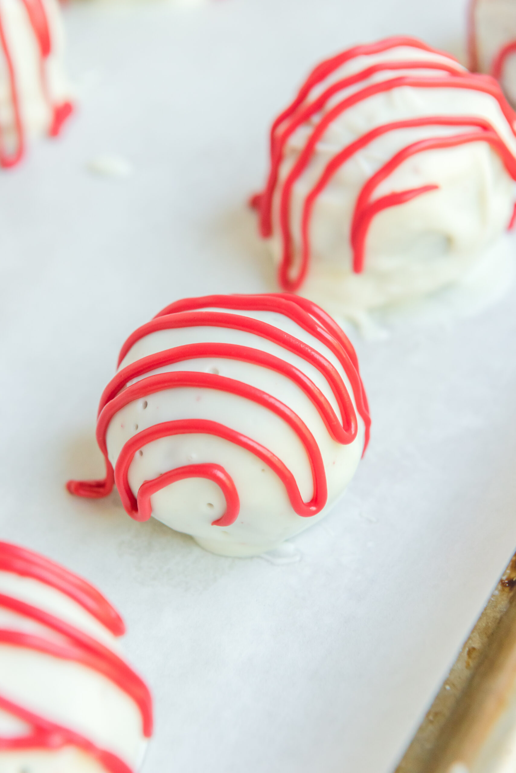 Close up shot of the red drizzle on top of a red velvet cake ball.