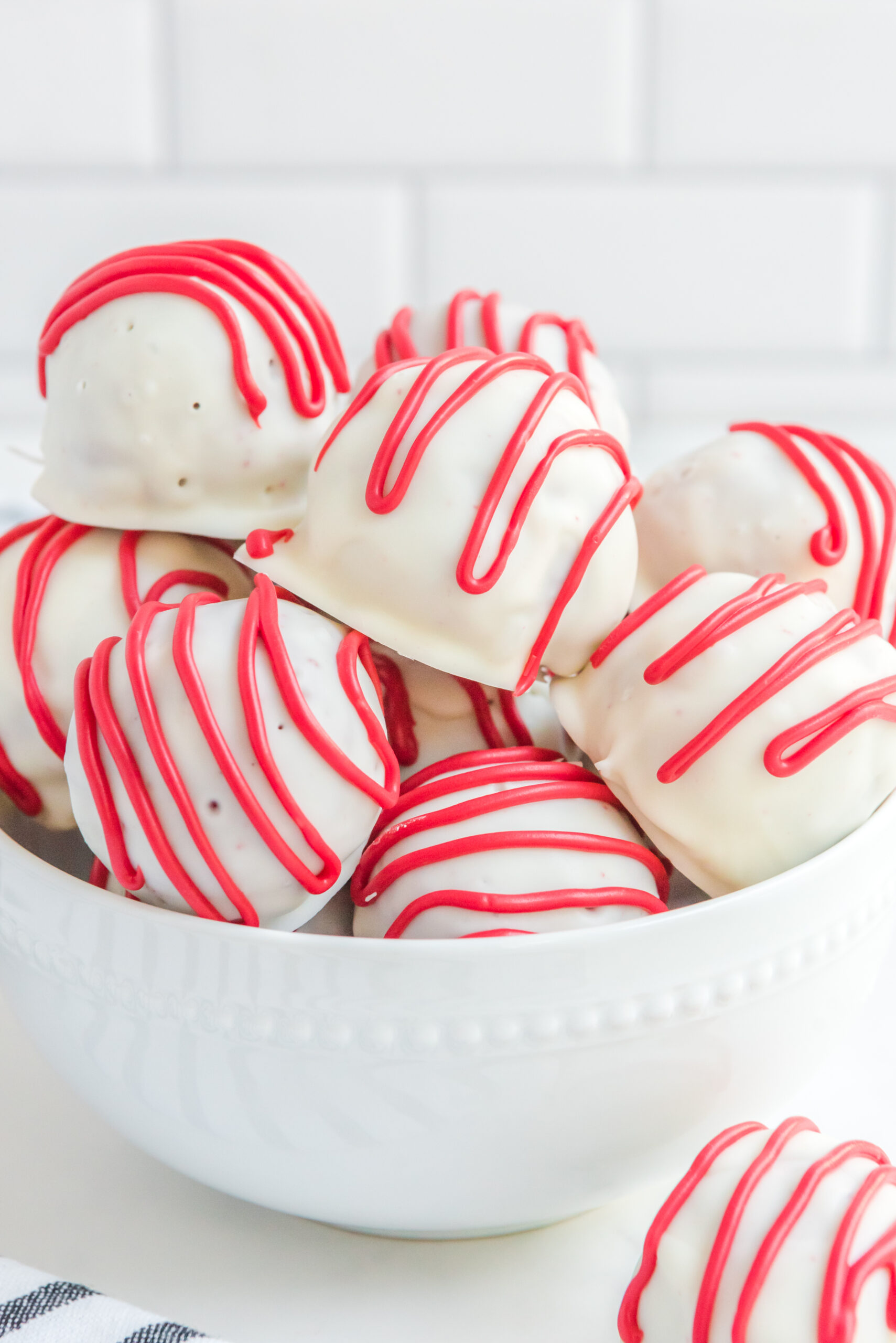 Red velvet cake balls stacked on top of each other in a white bowl.