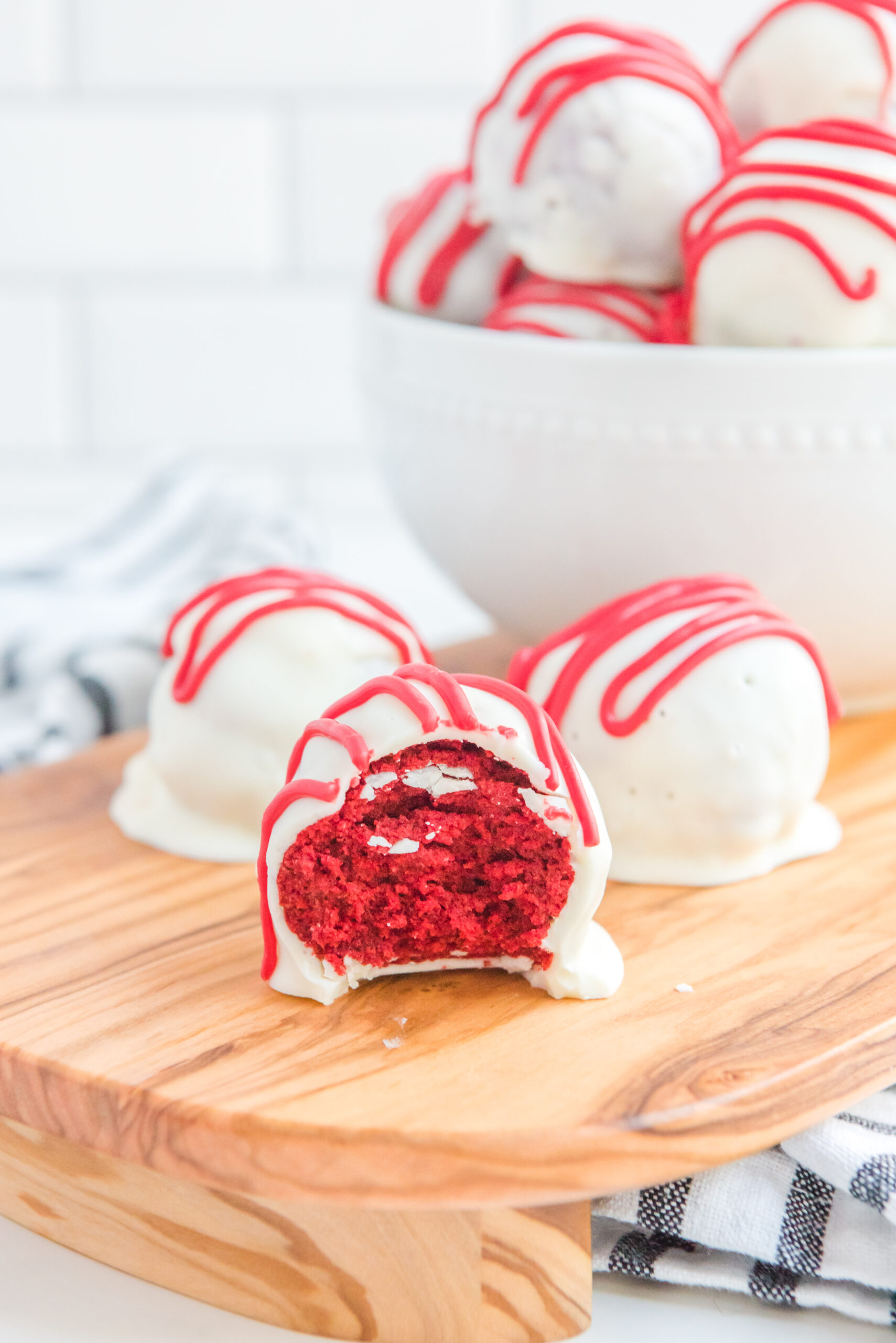 Three cake balls on a wooden serving tray, one has a bite removed showing the inside.