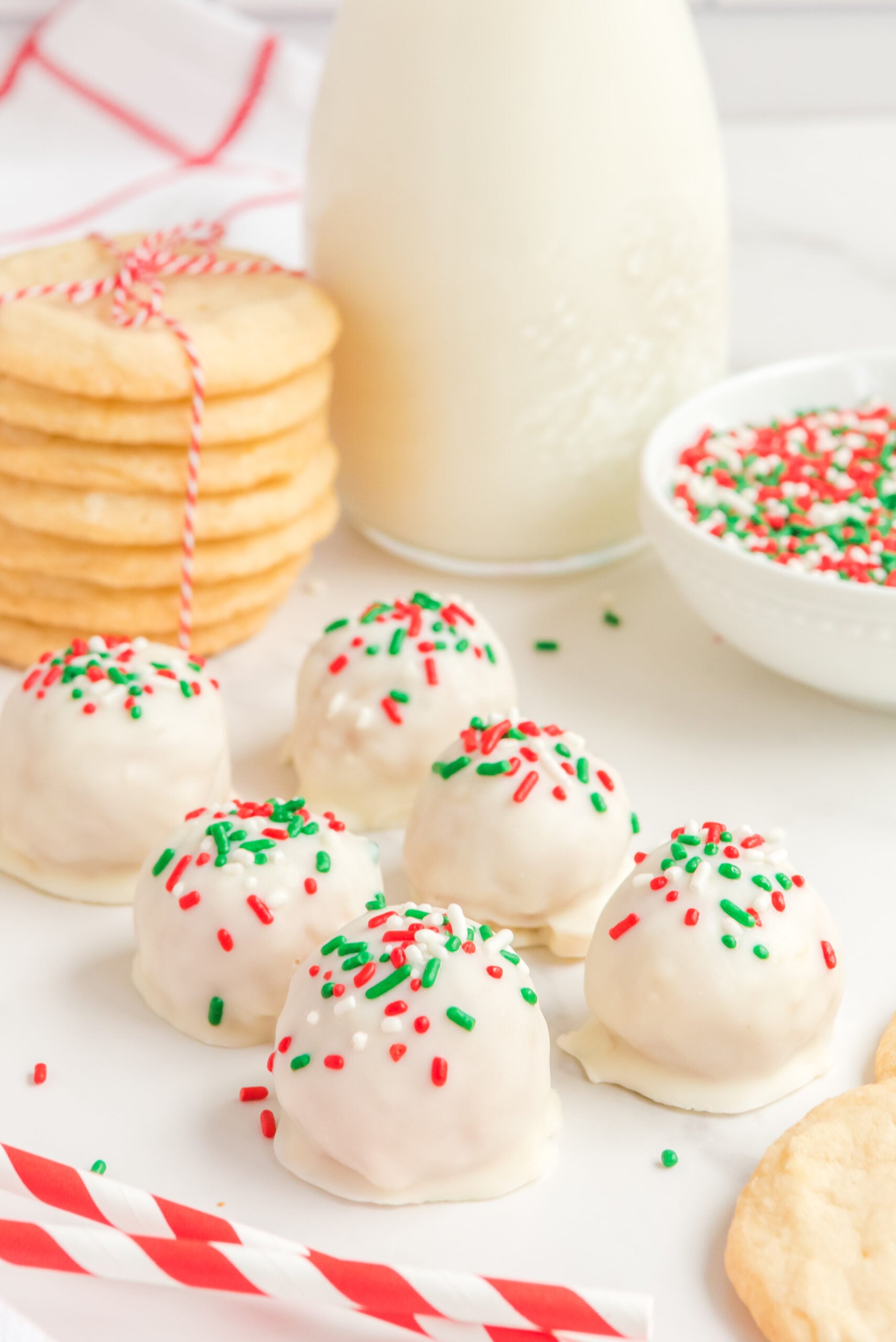 6 truffles on a white surface topped with red, green, and white sprinkles.