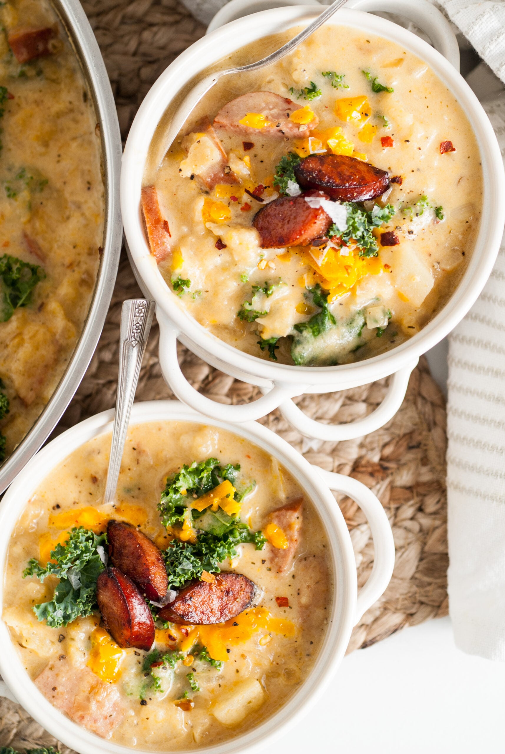 Overhead shot of the soup in two white bowls topped with Kale and cooked Kielbasa. 