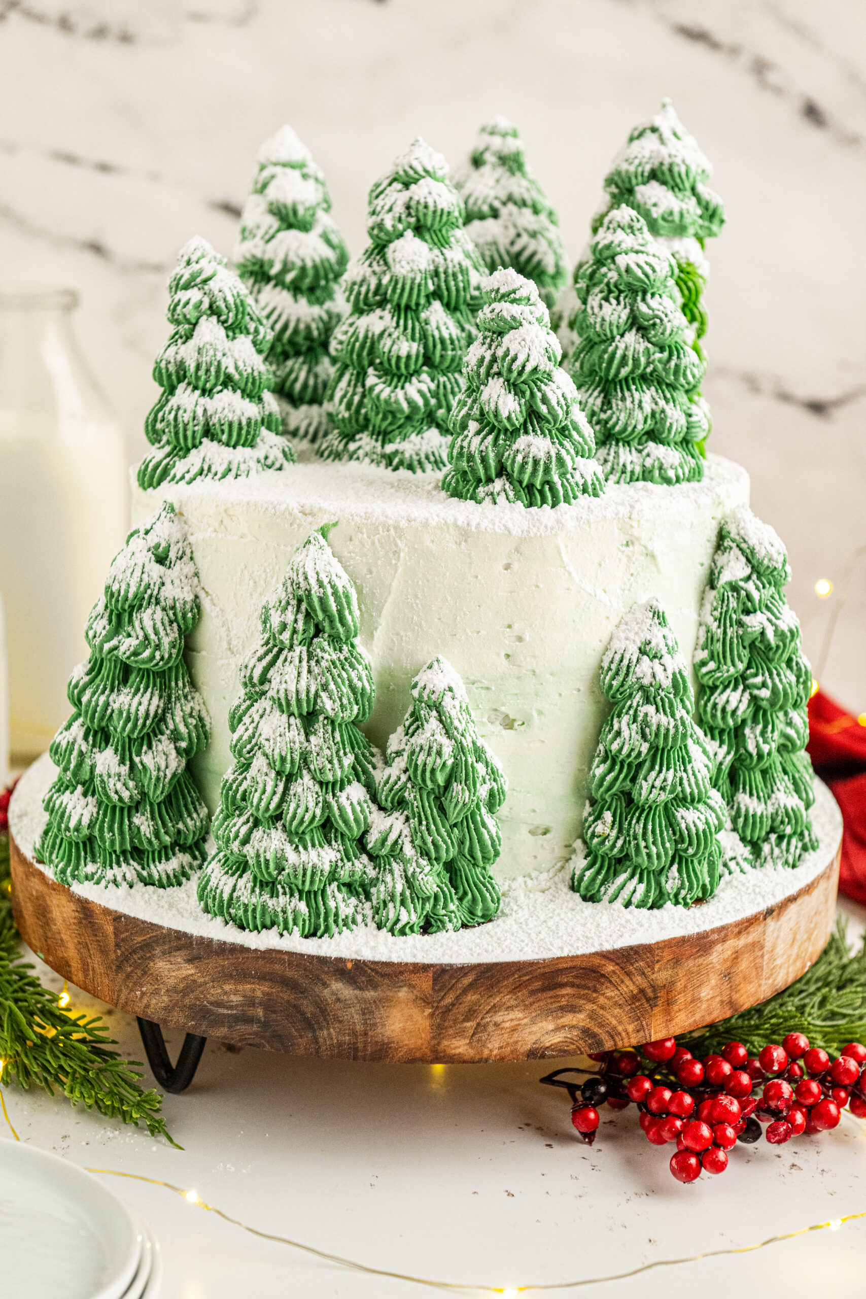 A white cake with green Christmas tree cones, sprinkled with powdered sugar.