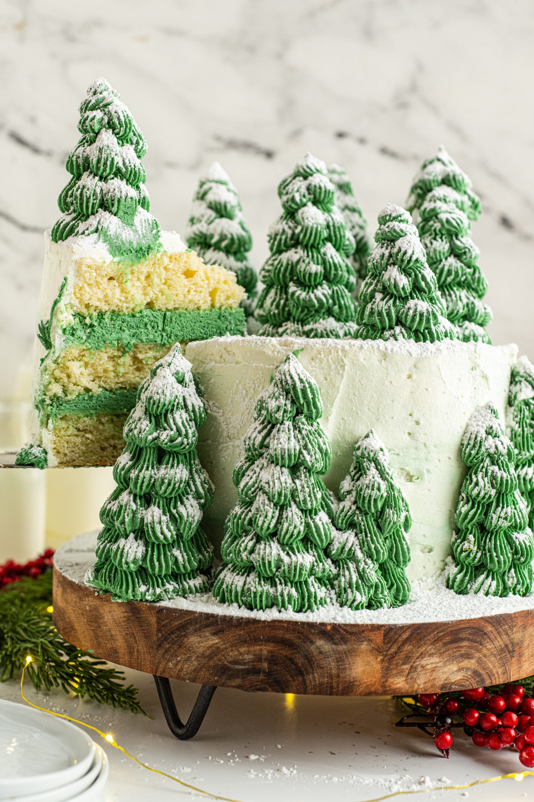Christmas tree cake on a wooden serving board with a piece being removed showing the white and green layers inside.