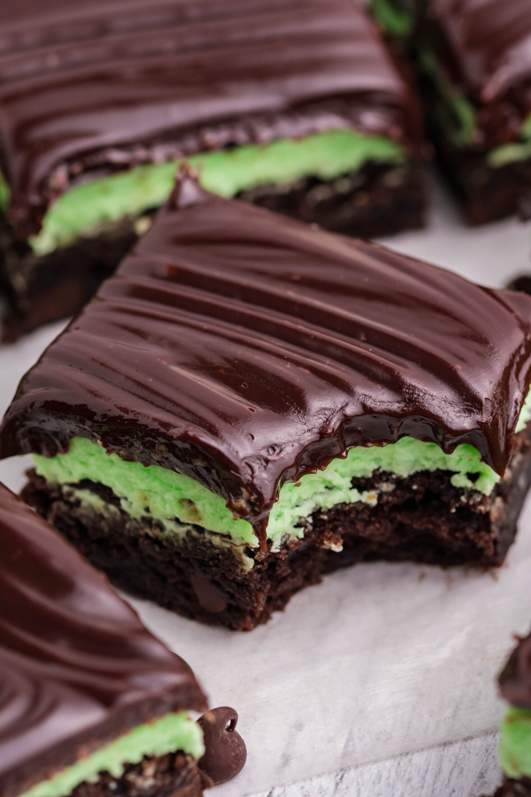 A bite removed from a mint chocolate brownie showing the three different layers.