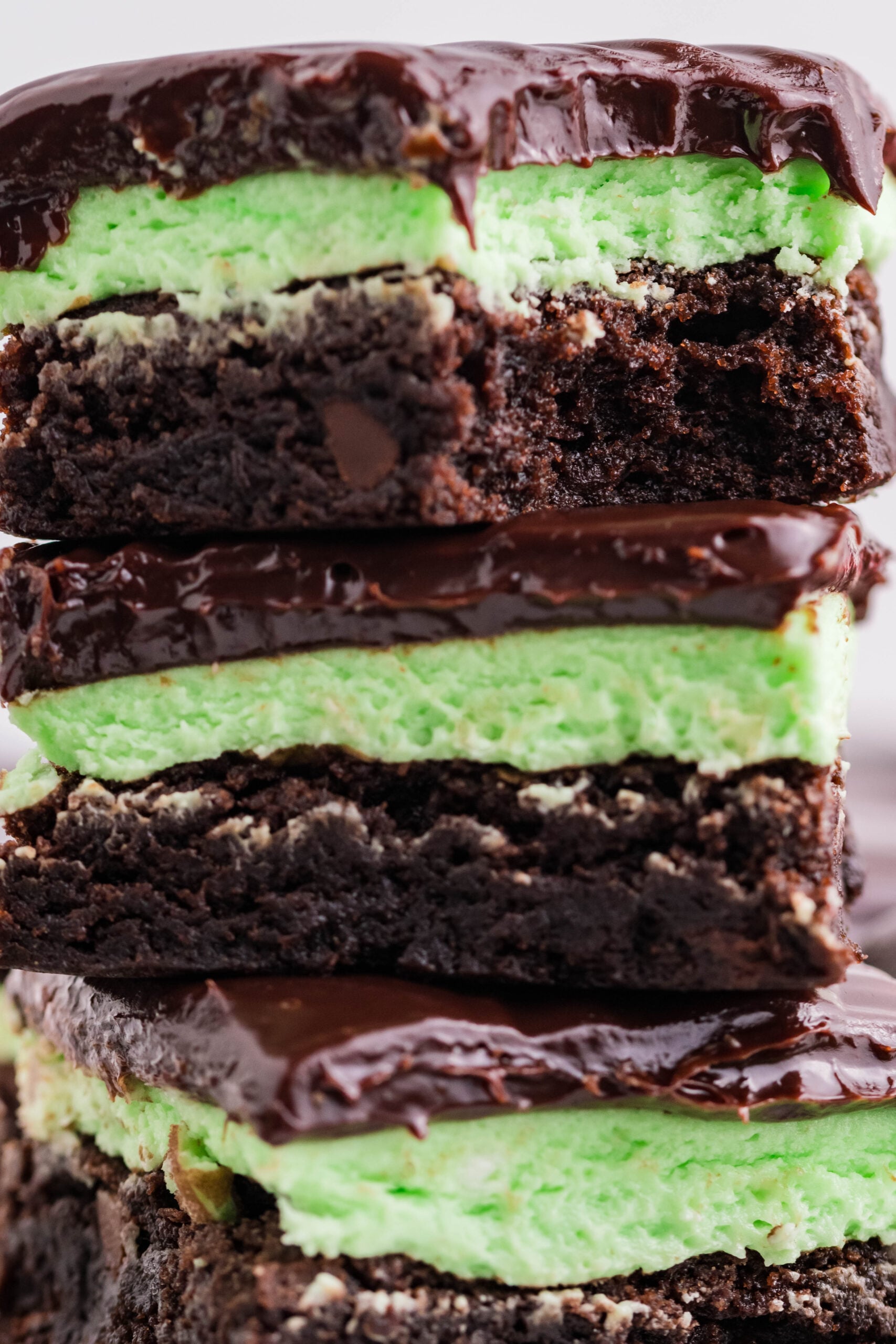 Three brownies stacked on top of each other with a bite removed from the top brownie.