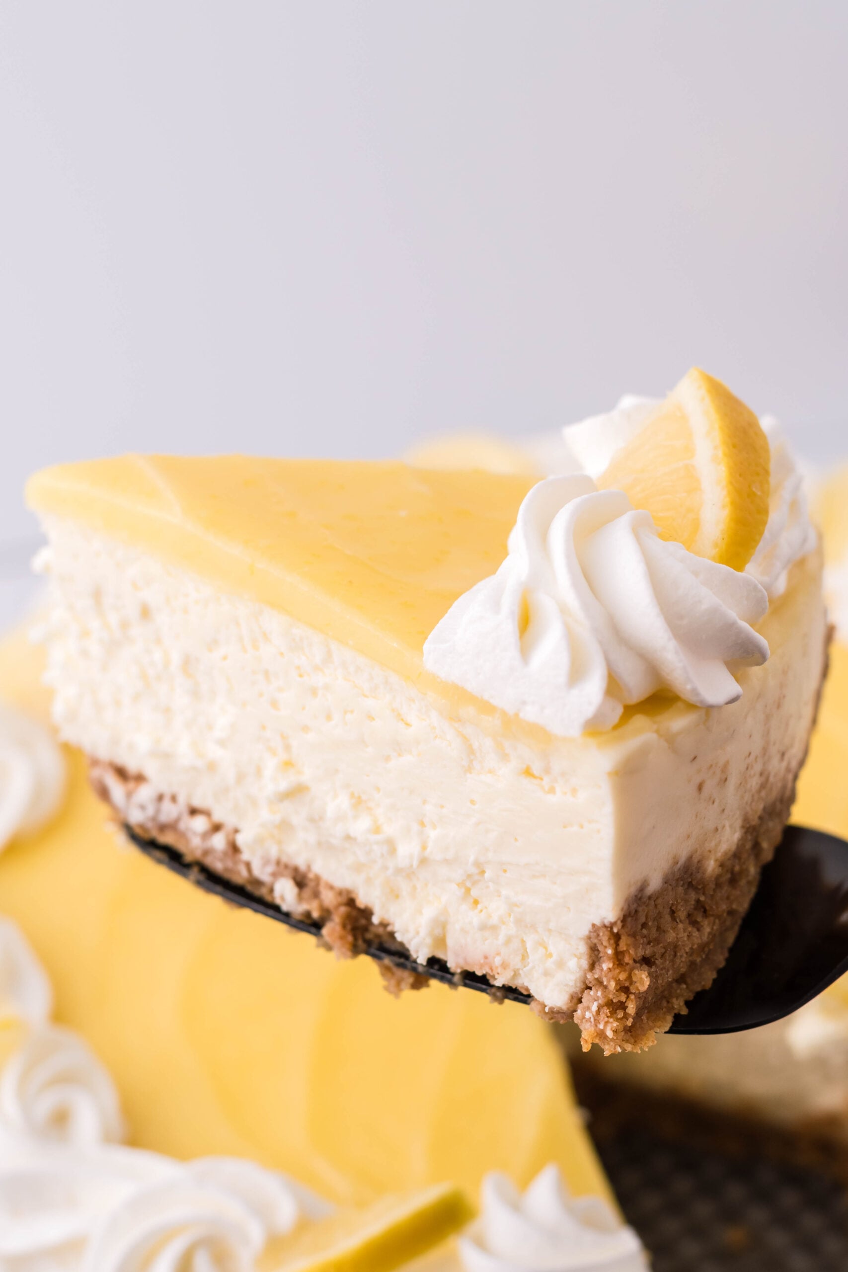 A slice of cheesecake being removed with a black spatula.