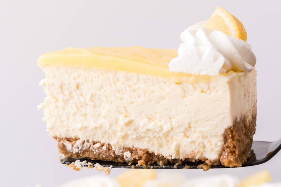 Side view of a slice of cheesecake being removed with a black spatula.