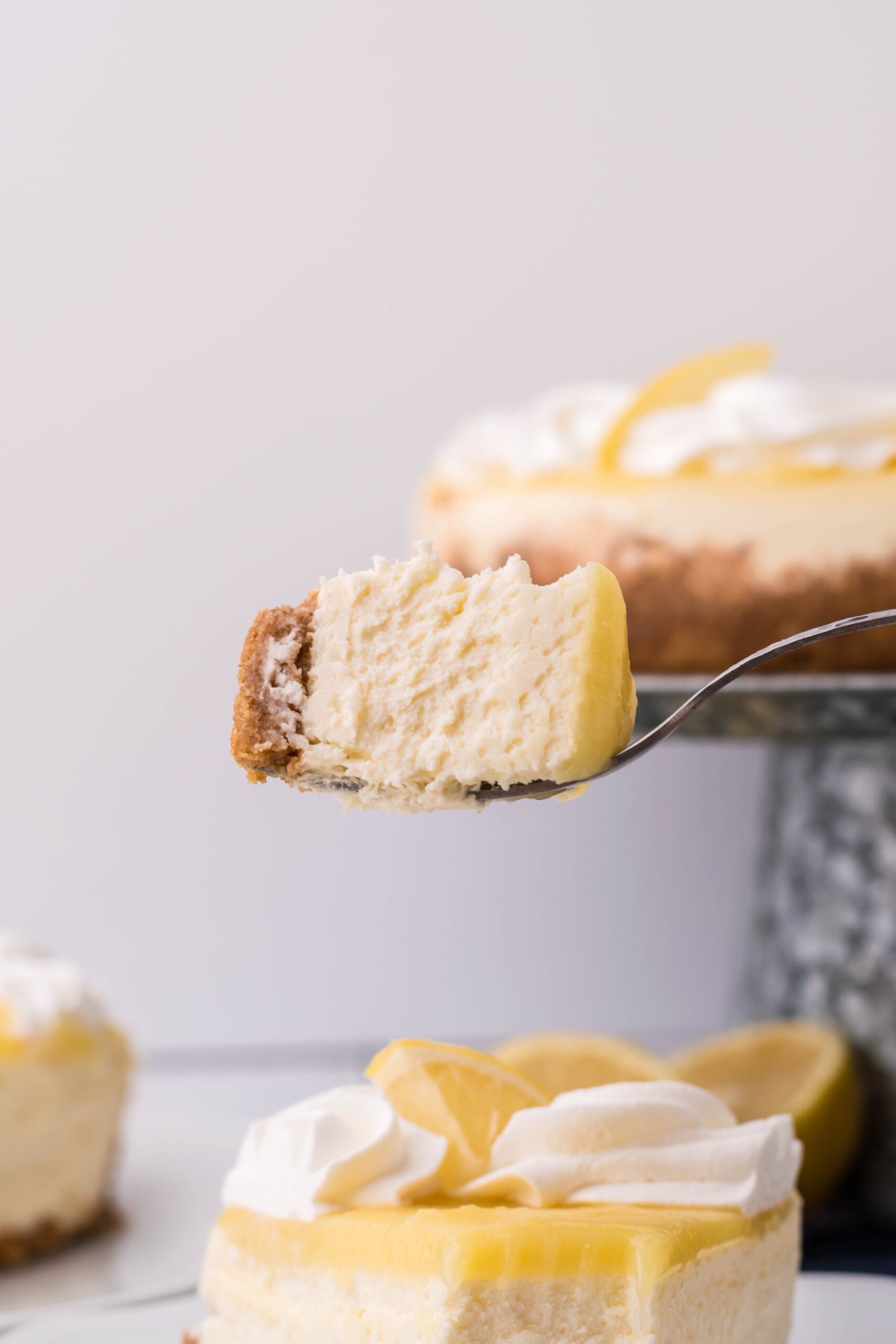 A bite of cheesecake being held up with a silver spoon showing the distinct three layers.