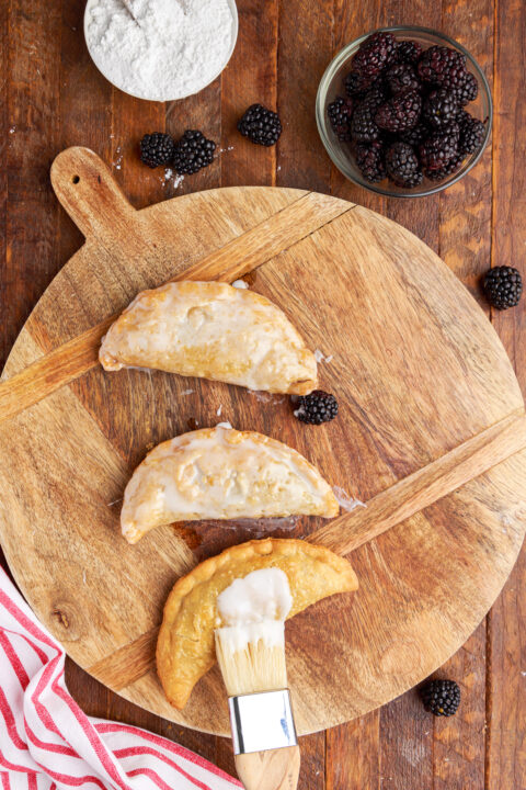 Overhead shot of brushing the glaze on top of the blackberry hand pies. 
