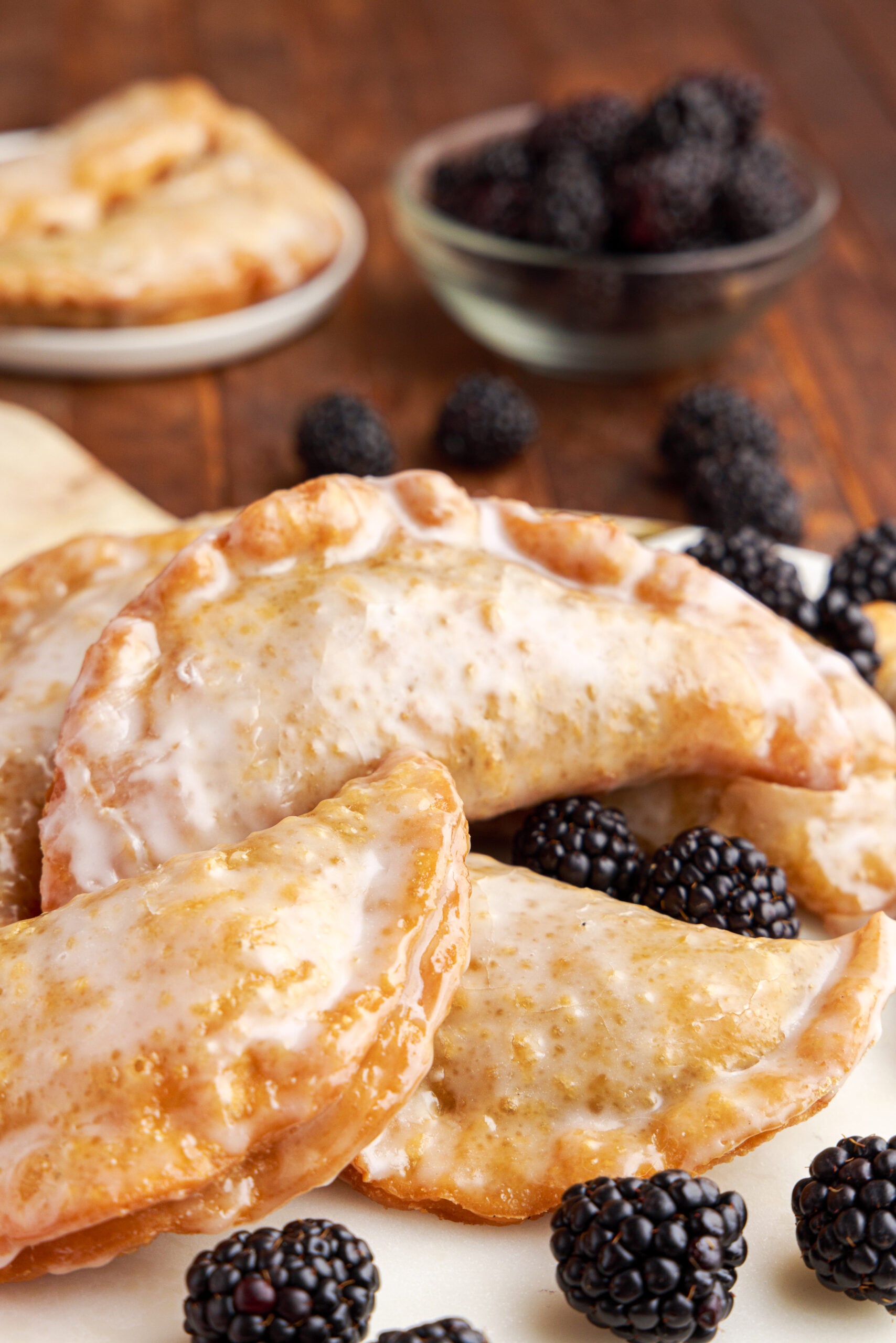 Hand pies stacked on a marble serving tray with fresh blackberries. 