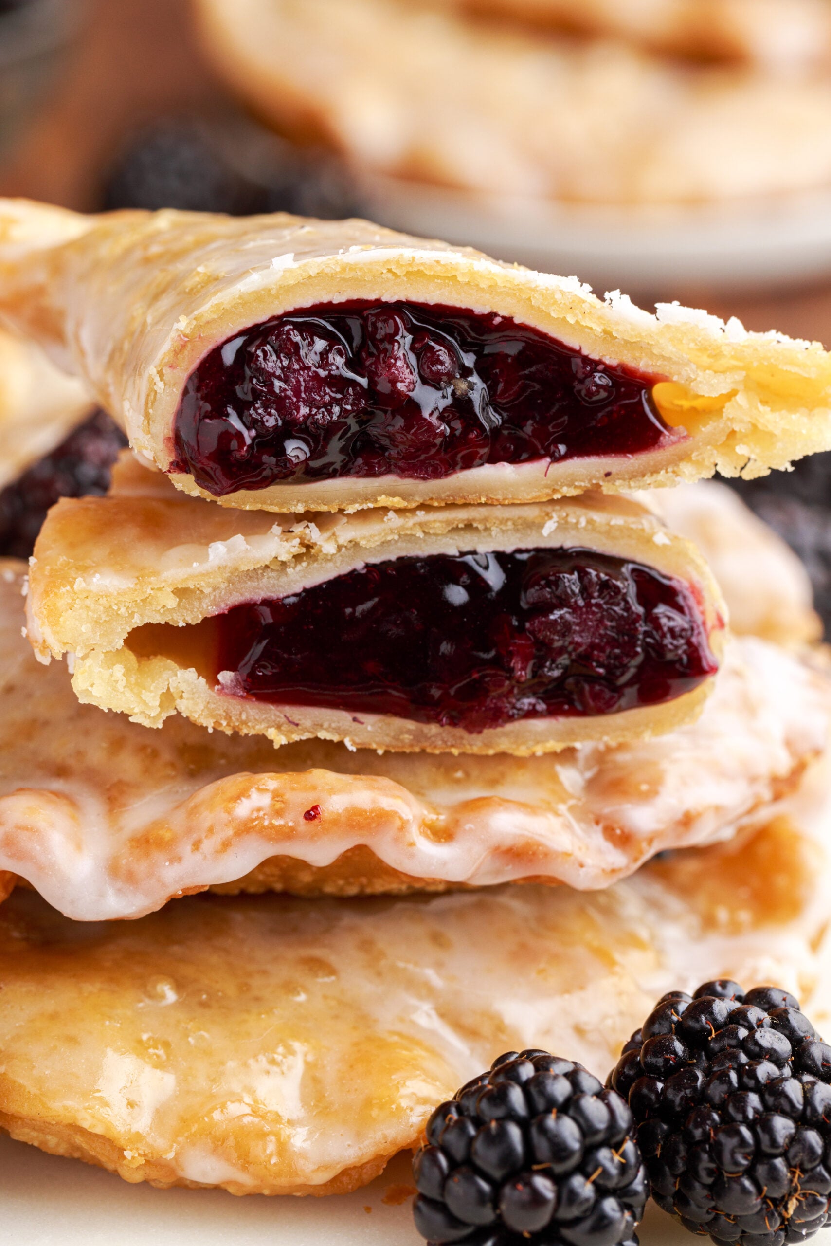 A blackberry hand pie cut in half and stacked on top of two other pies showing the berry filling. 