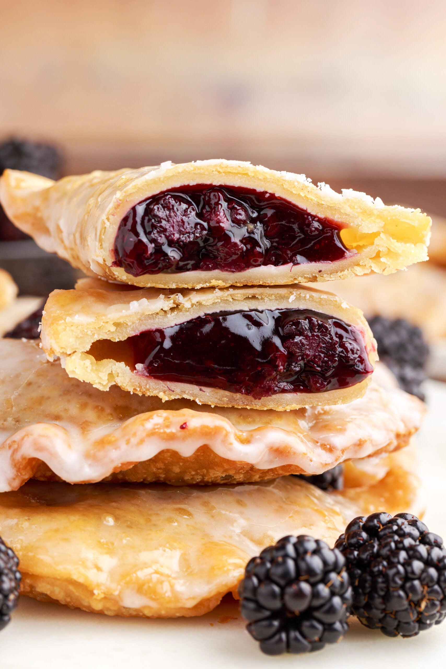 A blackberry hand pie cut in half and stacked on top of two other pies showing the berry filling. 
