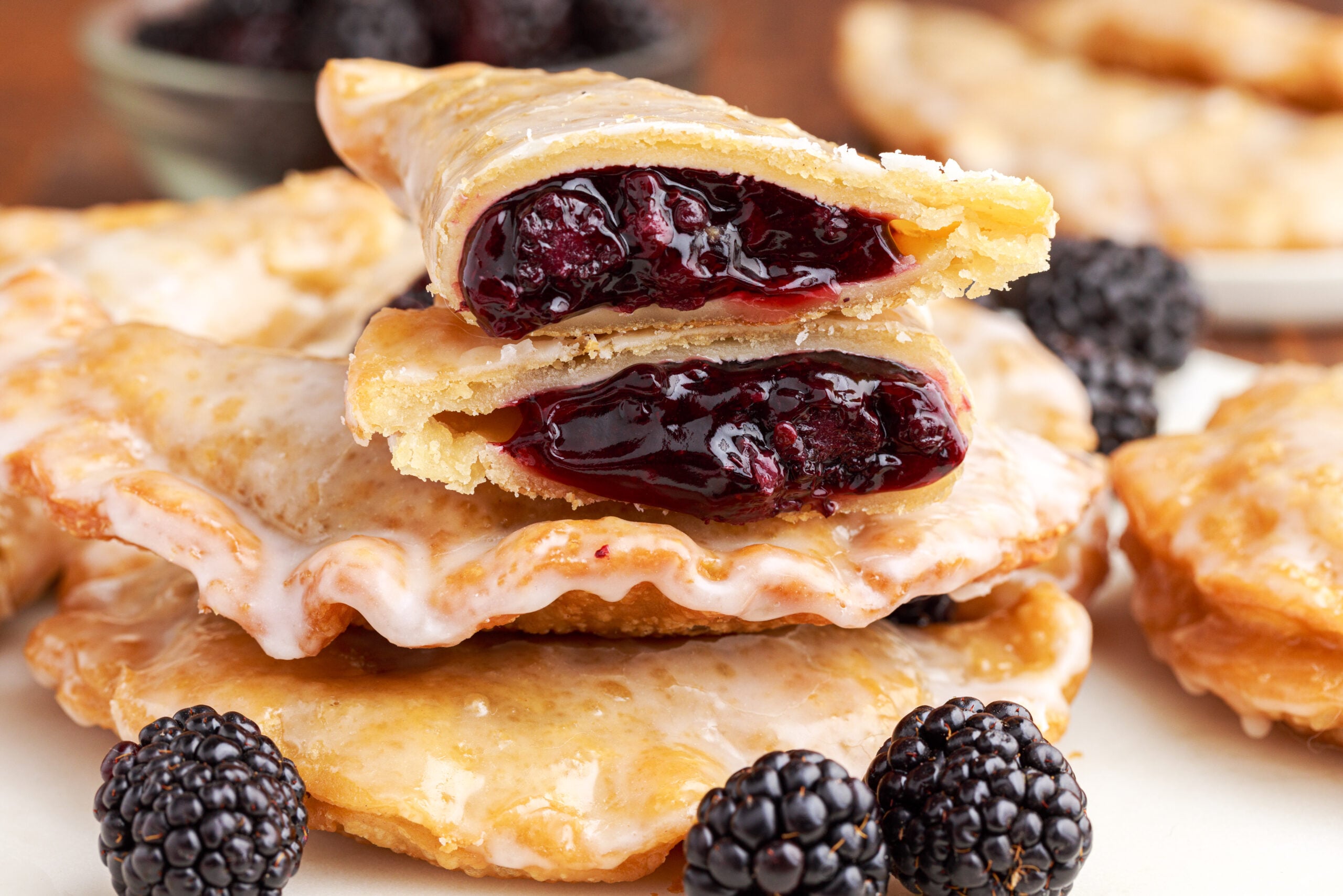 A blackberry hand pie cut in half and stacked on top of two other pies showing the berry filling. 