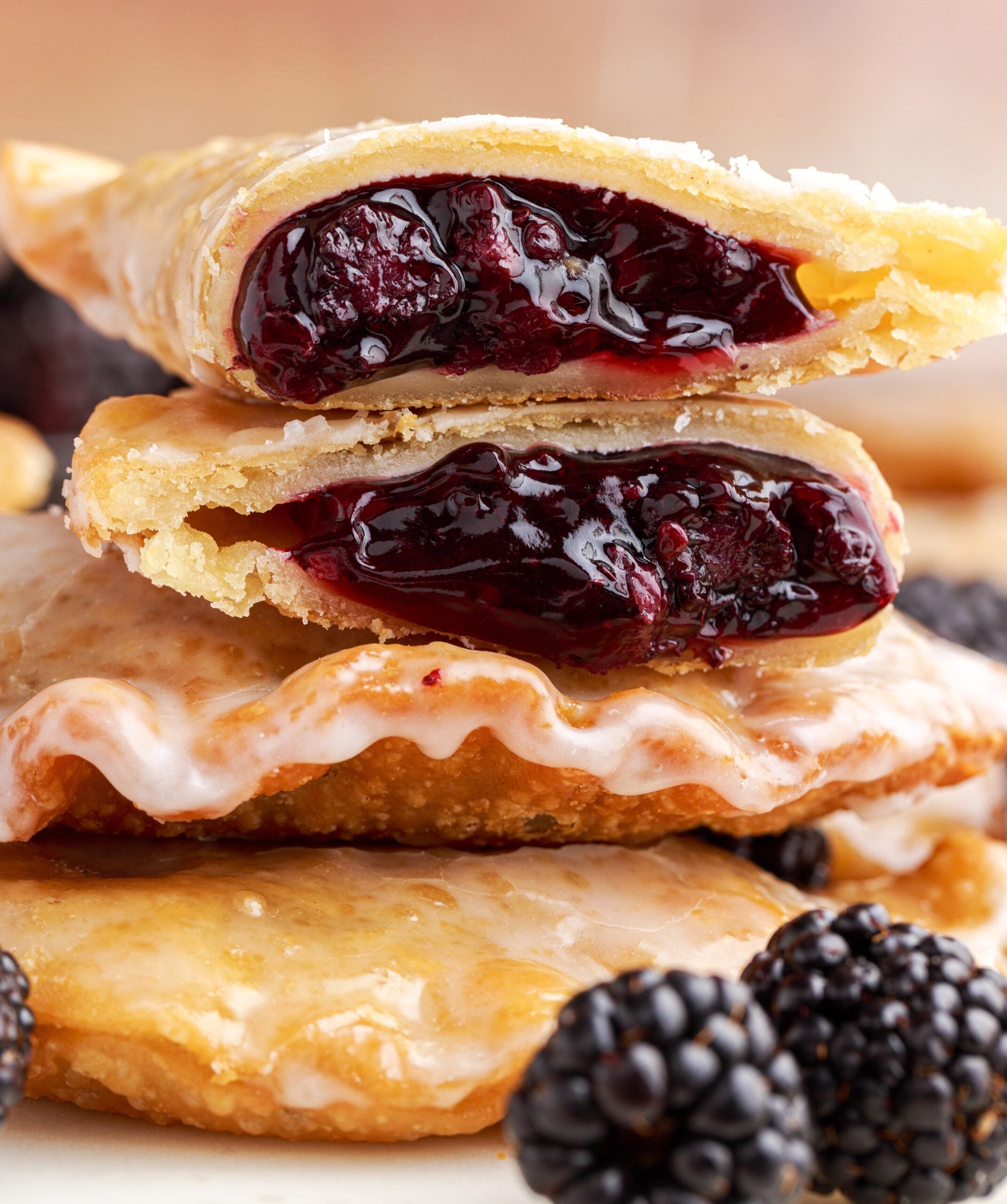 A blackberry hand pie cut in half and stacked on top of two other pies showing the berry filling. 