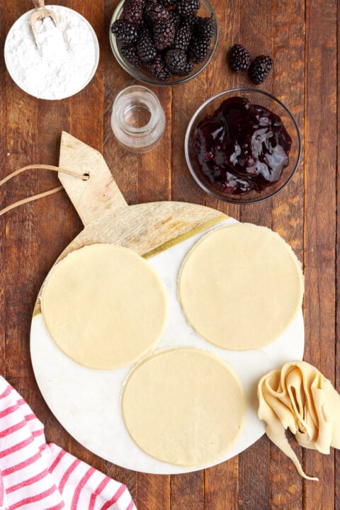 three circle of pie dough on a marble serving tray showing the in process of creating this recipe. 