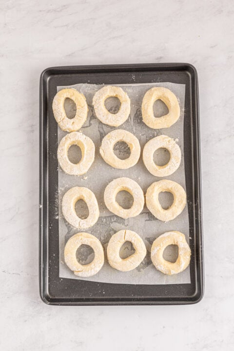 The donuts cut on a baking sheet ready to fry.