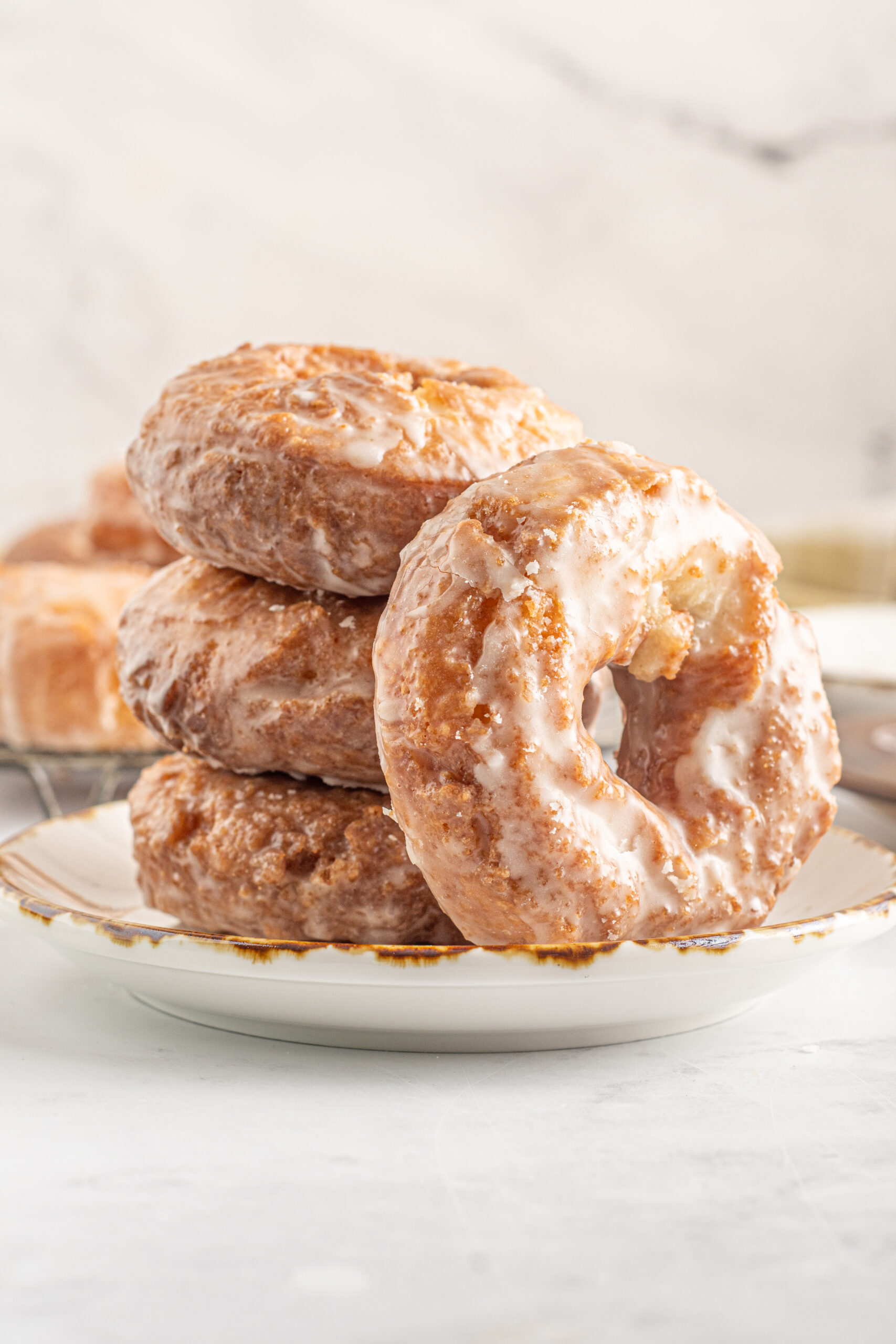 4 old fashioned donuts stacked on a tan and brown plate.