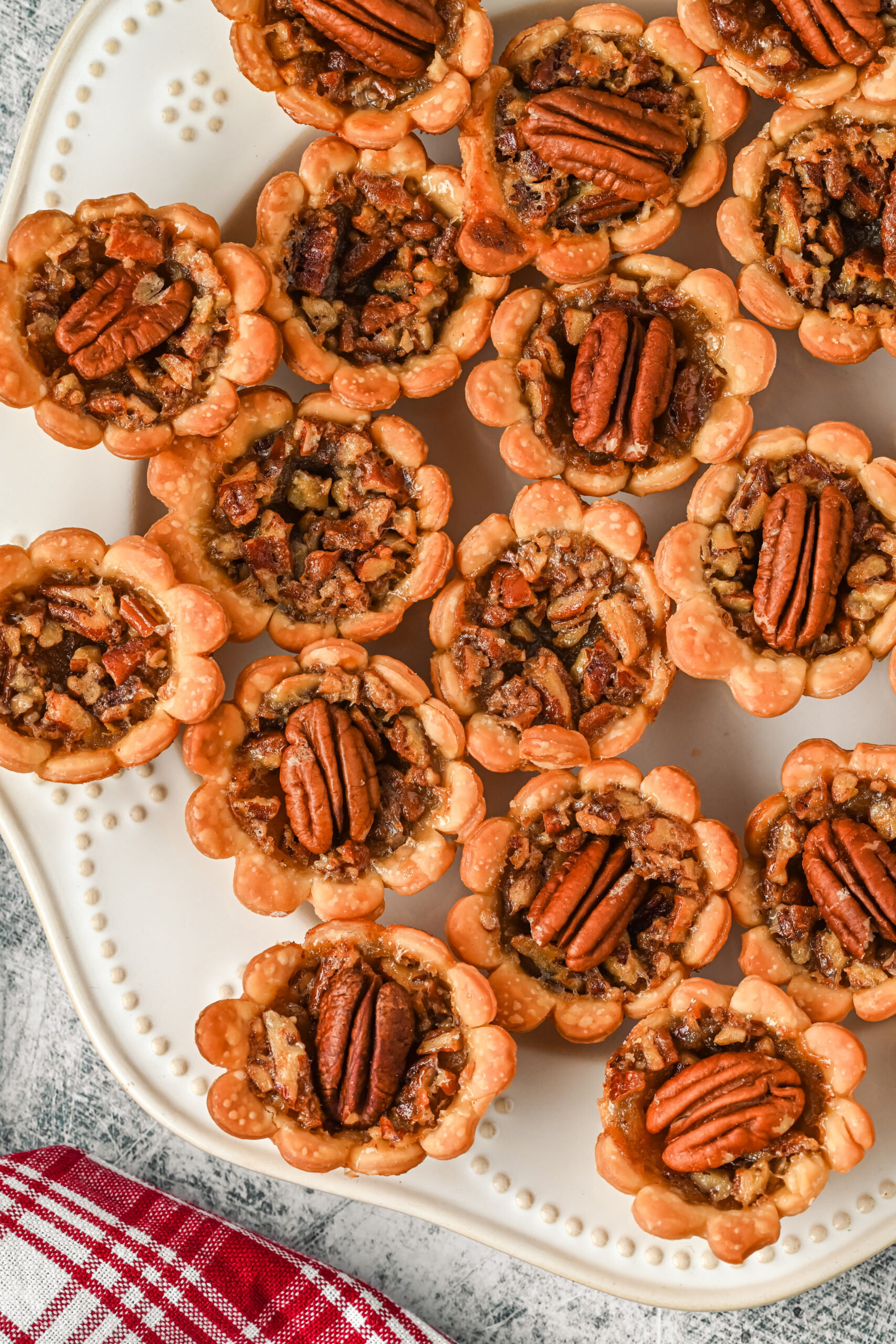 Overhead view of mini pecan pies on a white serving tray.