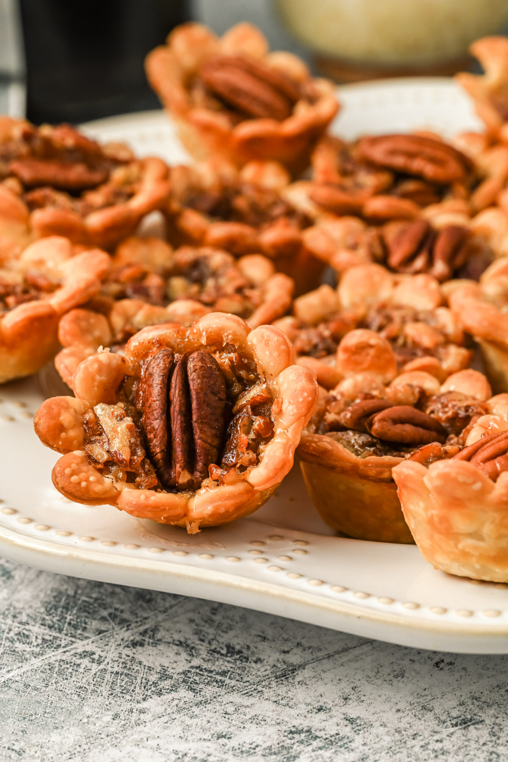 Side view of mini pecan pies on a white serving tray.