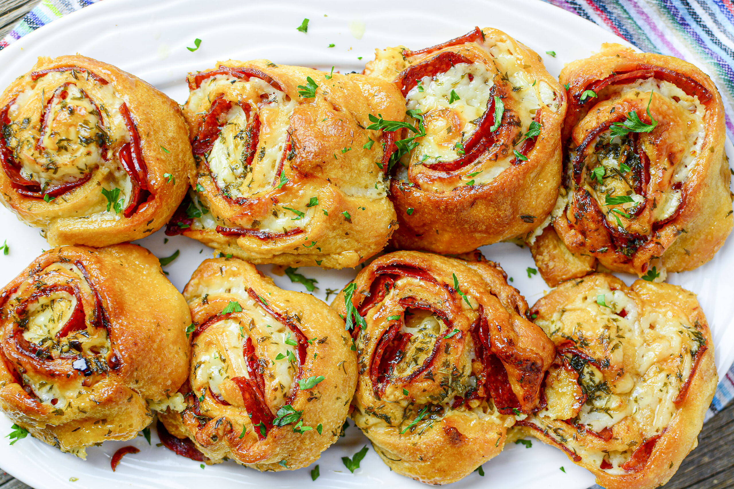 Pizza pinwheels lined up on a large white serving tray 