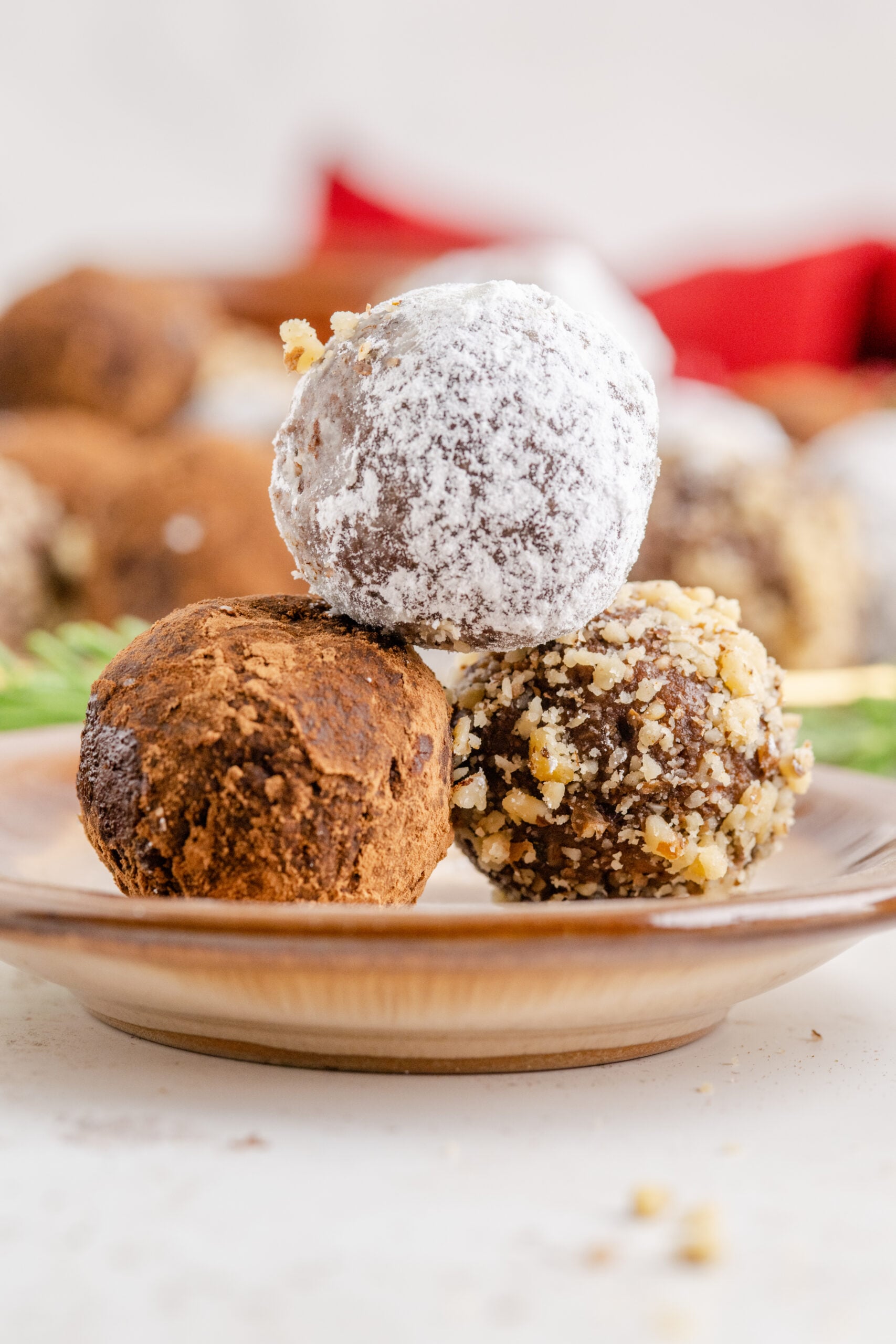 Three rum balls stacked on a brown dessert plate.