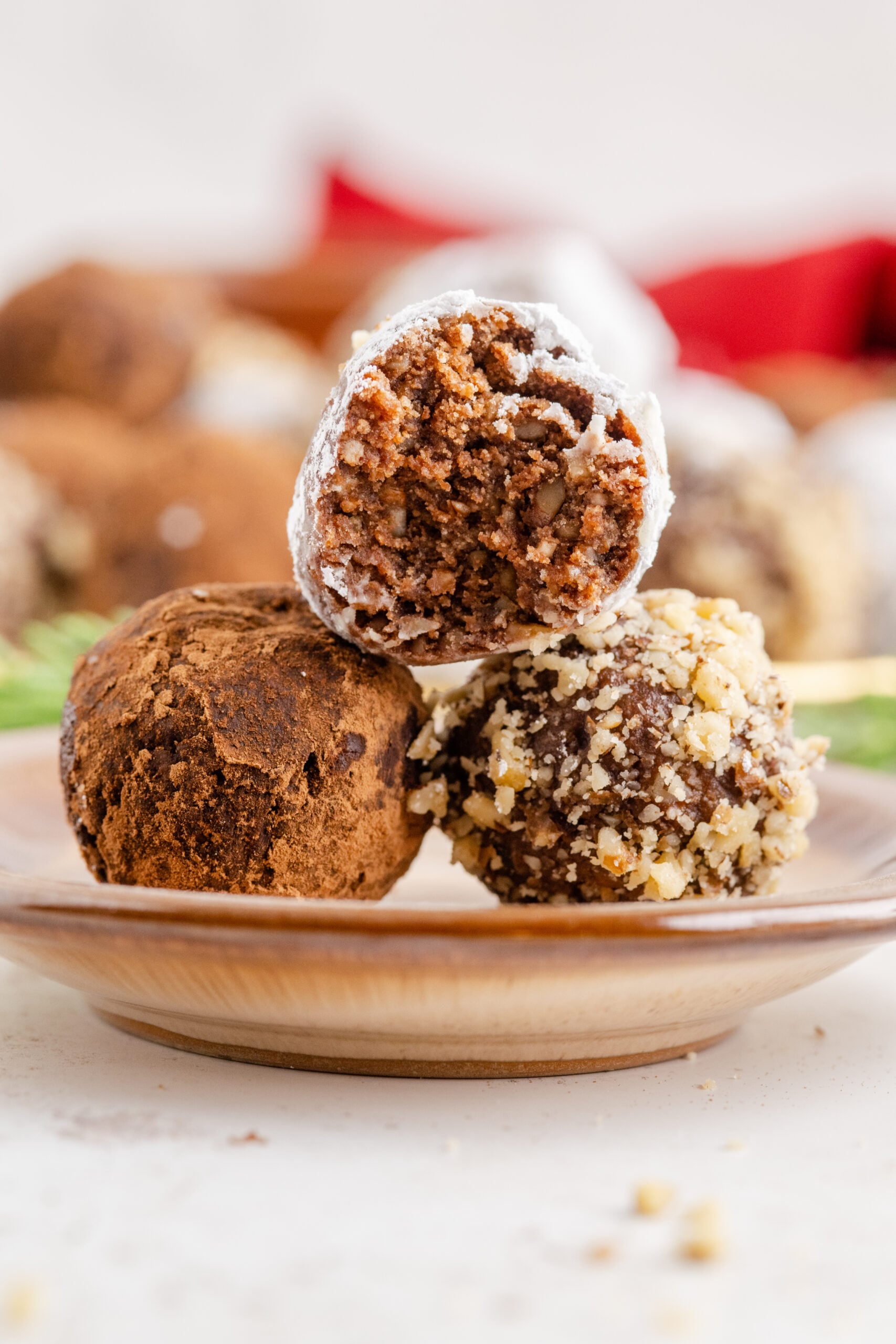 Three rum balls stacked on a brown dessert plate with a bite removed from the top showing the inside.