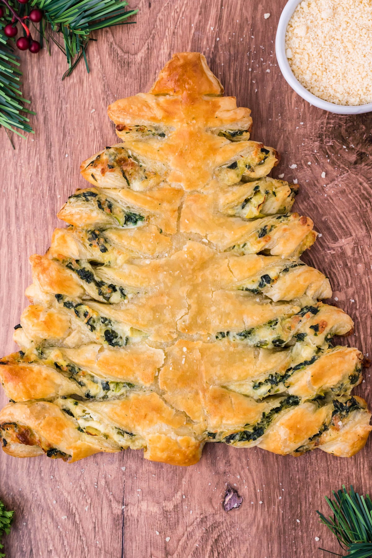 Overhead view of spinach dip pull apart Christmas tree bread on a dark wood background.