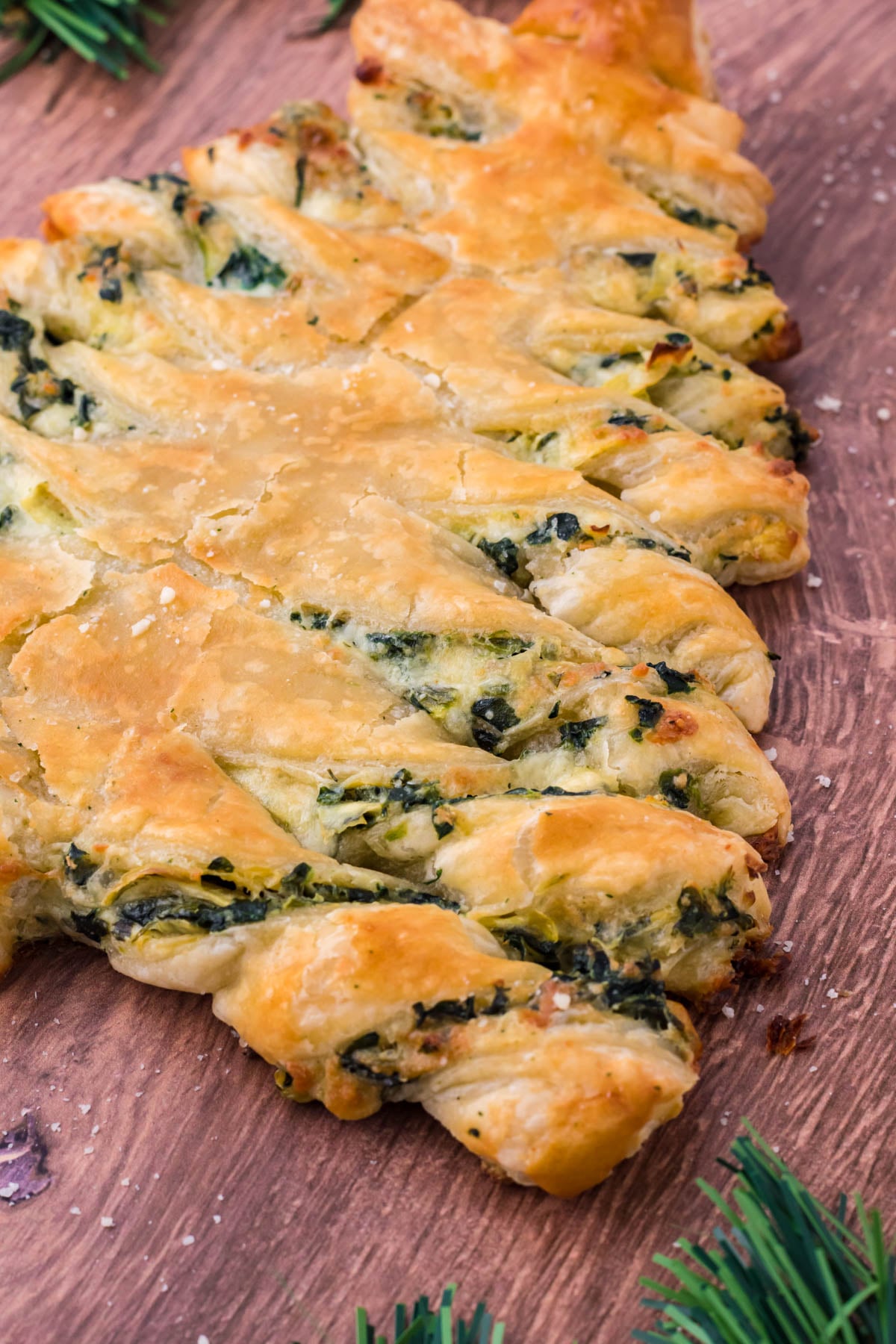 Side view of spinach dip pull apart Christmas tree bread on a dark wood background.