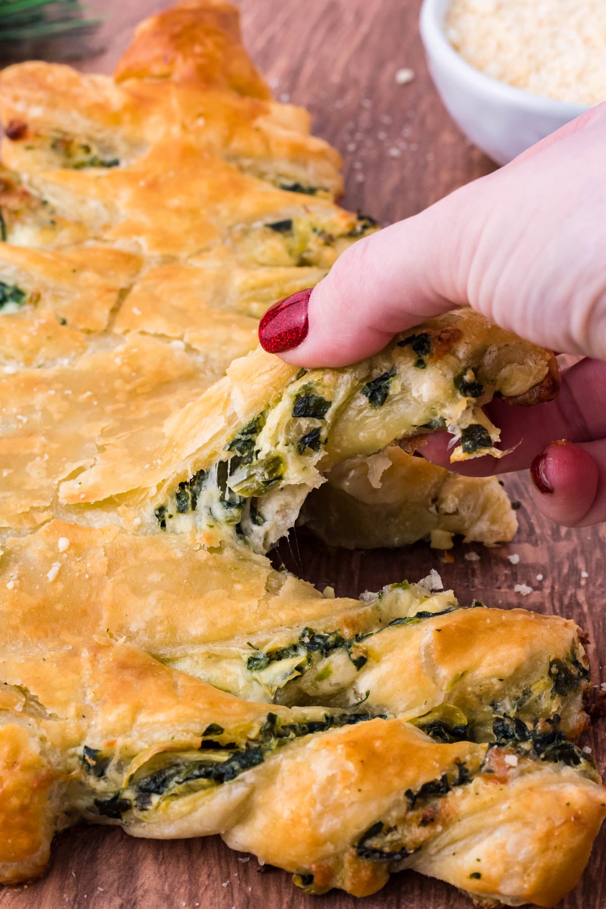 Photo of a piece of pull apart bread being removed showing the cheesy inside.