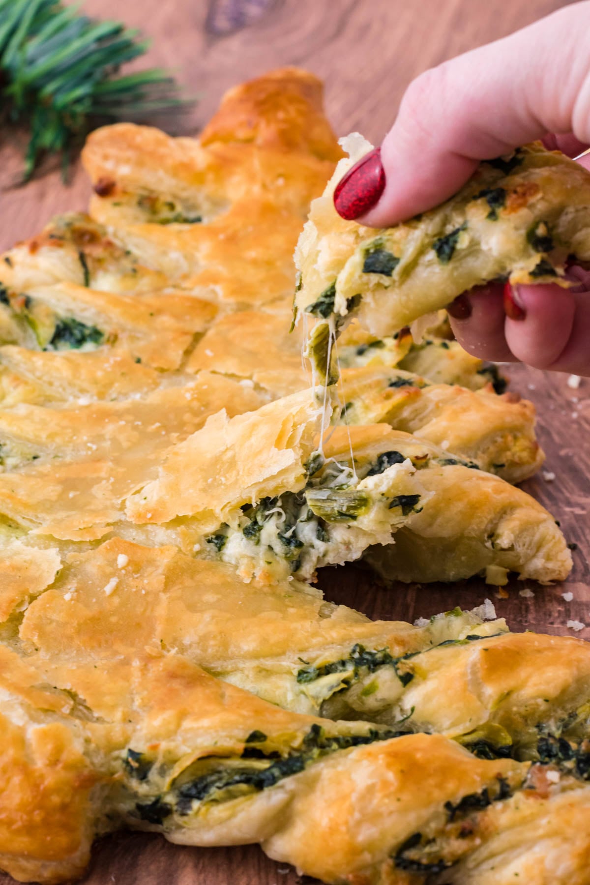 Photo of a piece of pull apart bread being removed showing the cheesy inside.