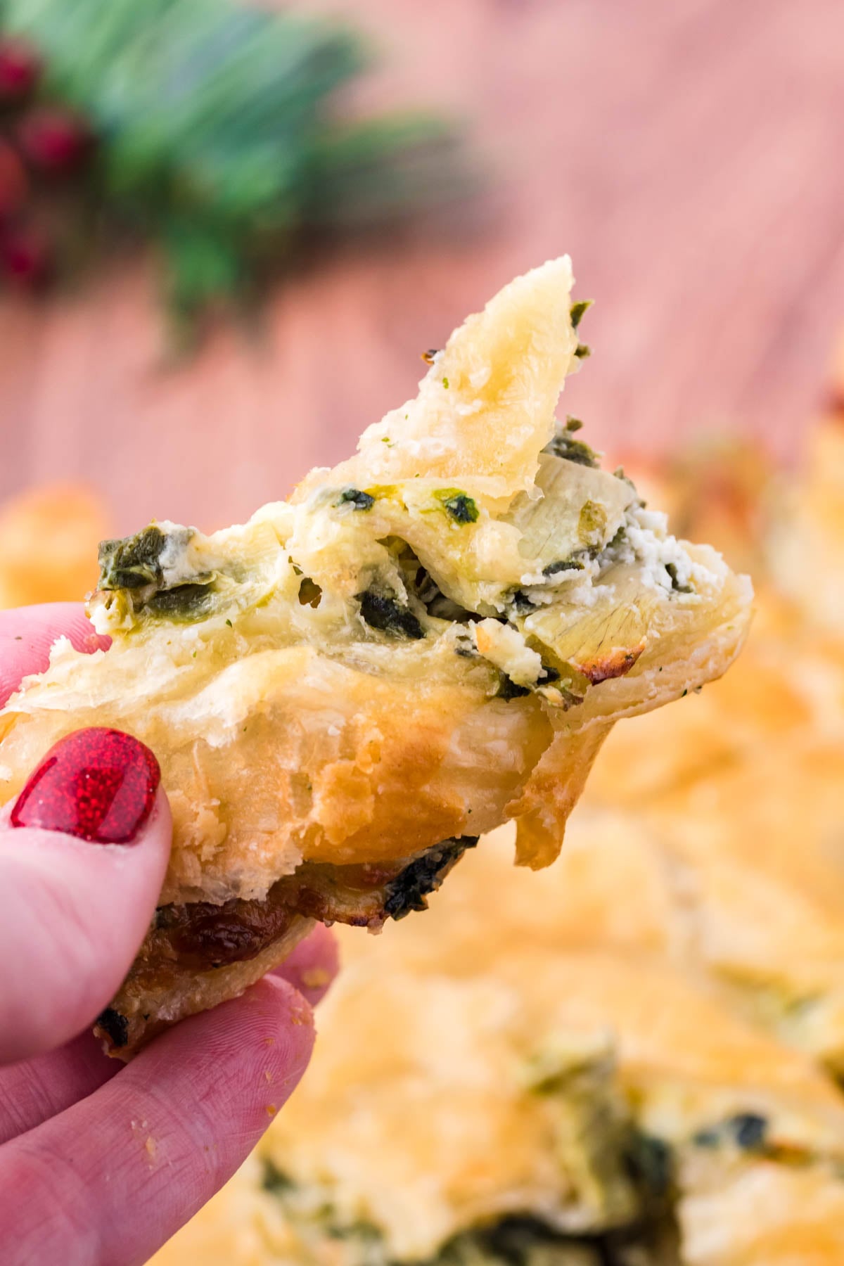 A piece of spinach dip pull apart bread being held up showing the flakey outside layer.