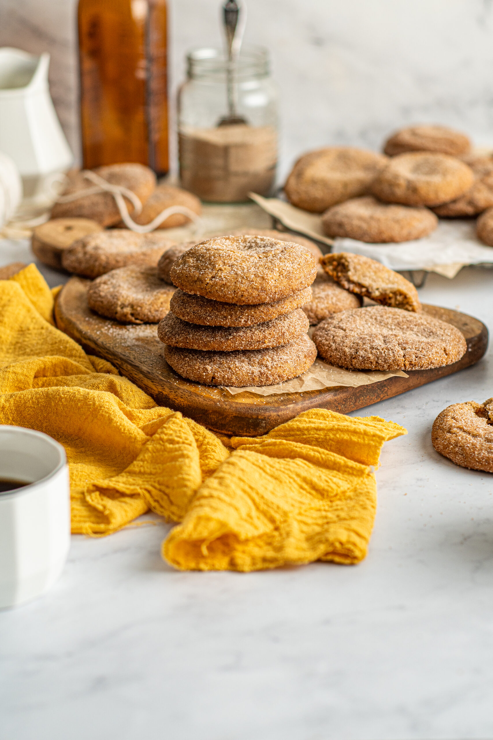 Side view of four stacked Stuffed Churro Cookies on a wooden board with a mustard yellow linen.