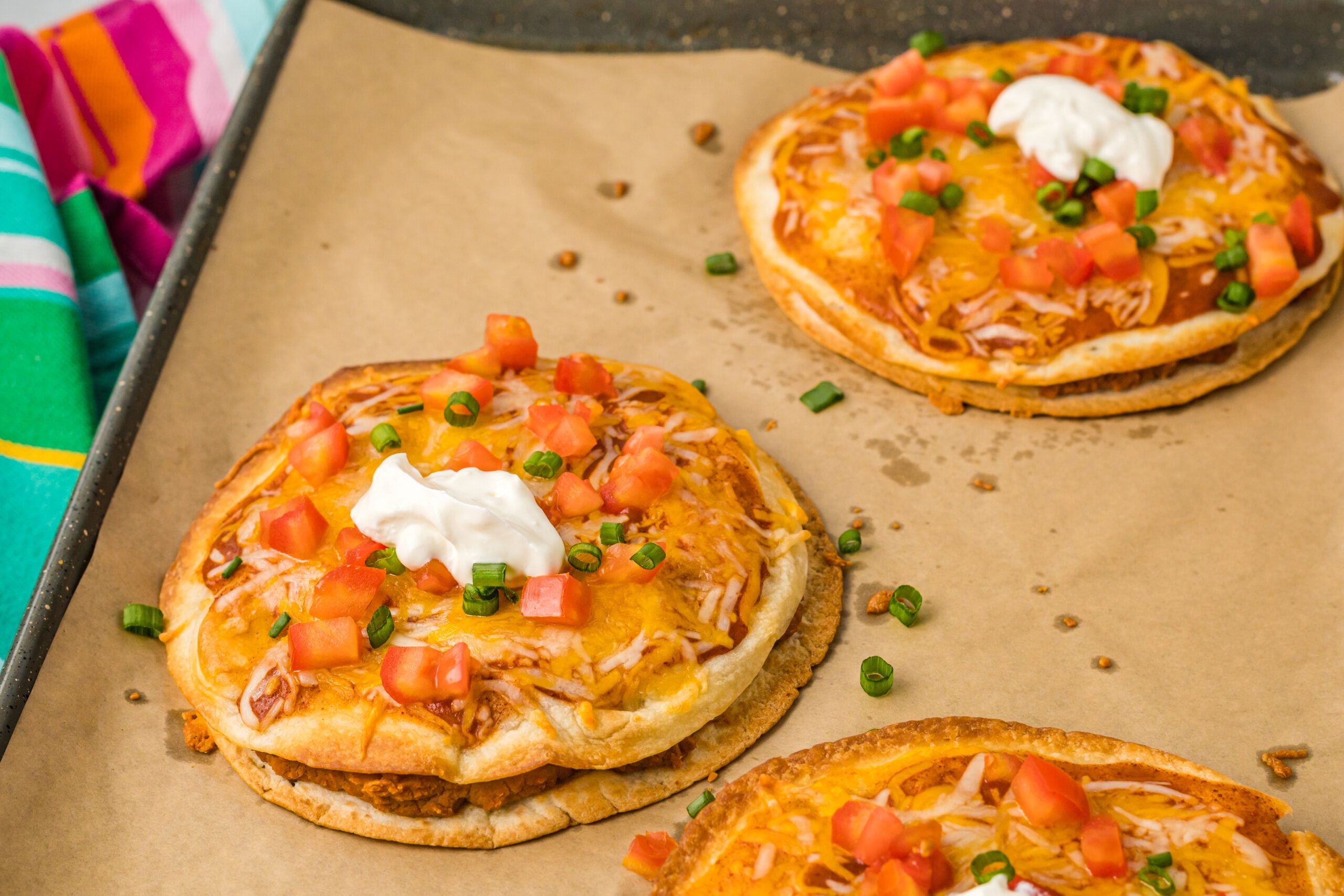 three mexican pizzas on brown paper lining a baking sheet