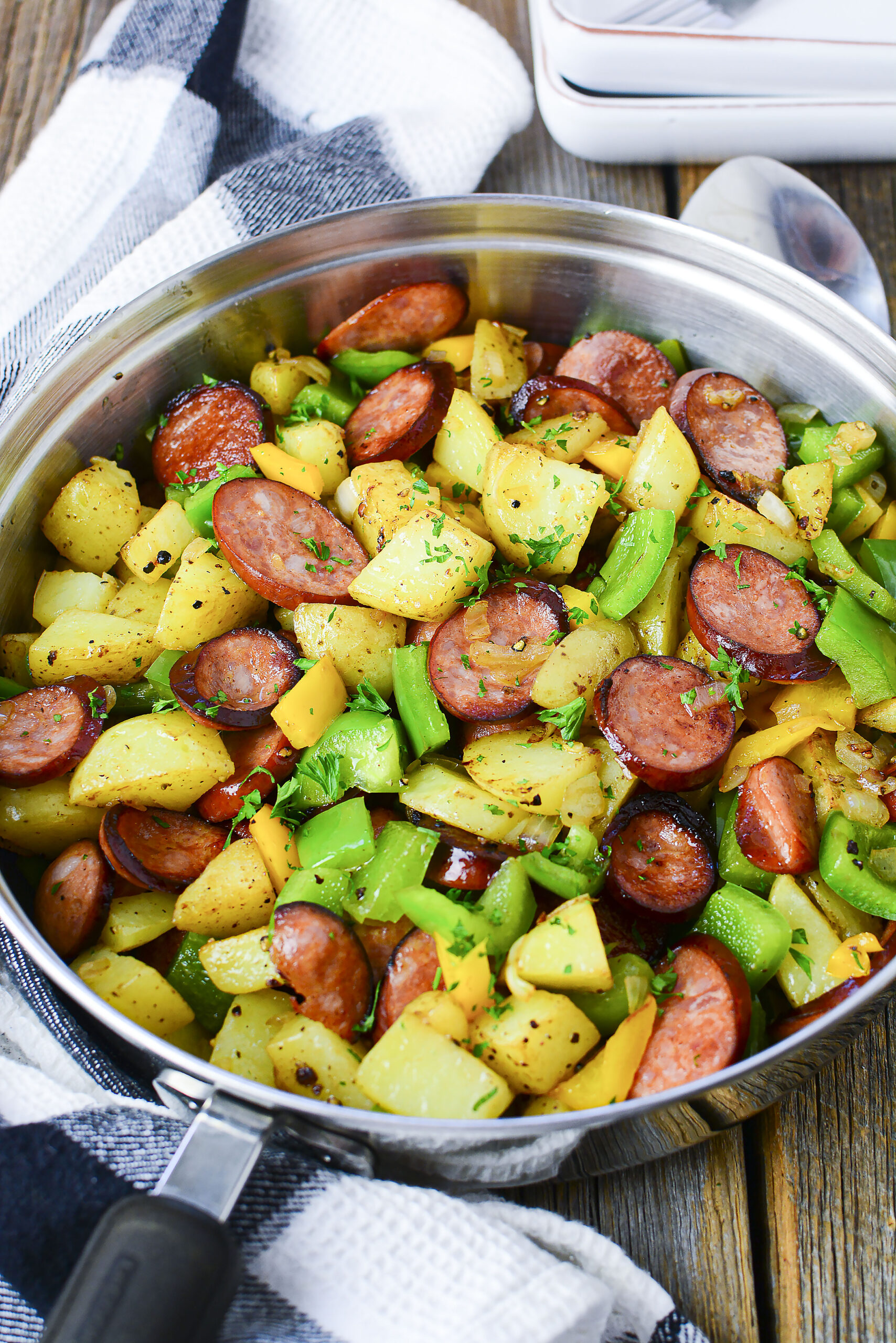 Overhead view of Sausage peppers and potatoes in a silver skillet.