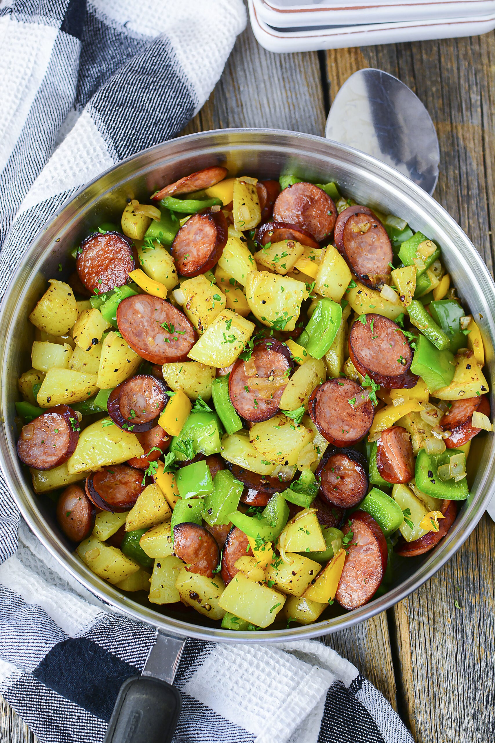 Overhead view of Sausage peppers and potatoes in a silver skillet.