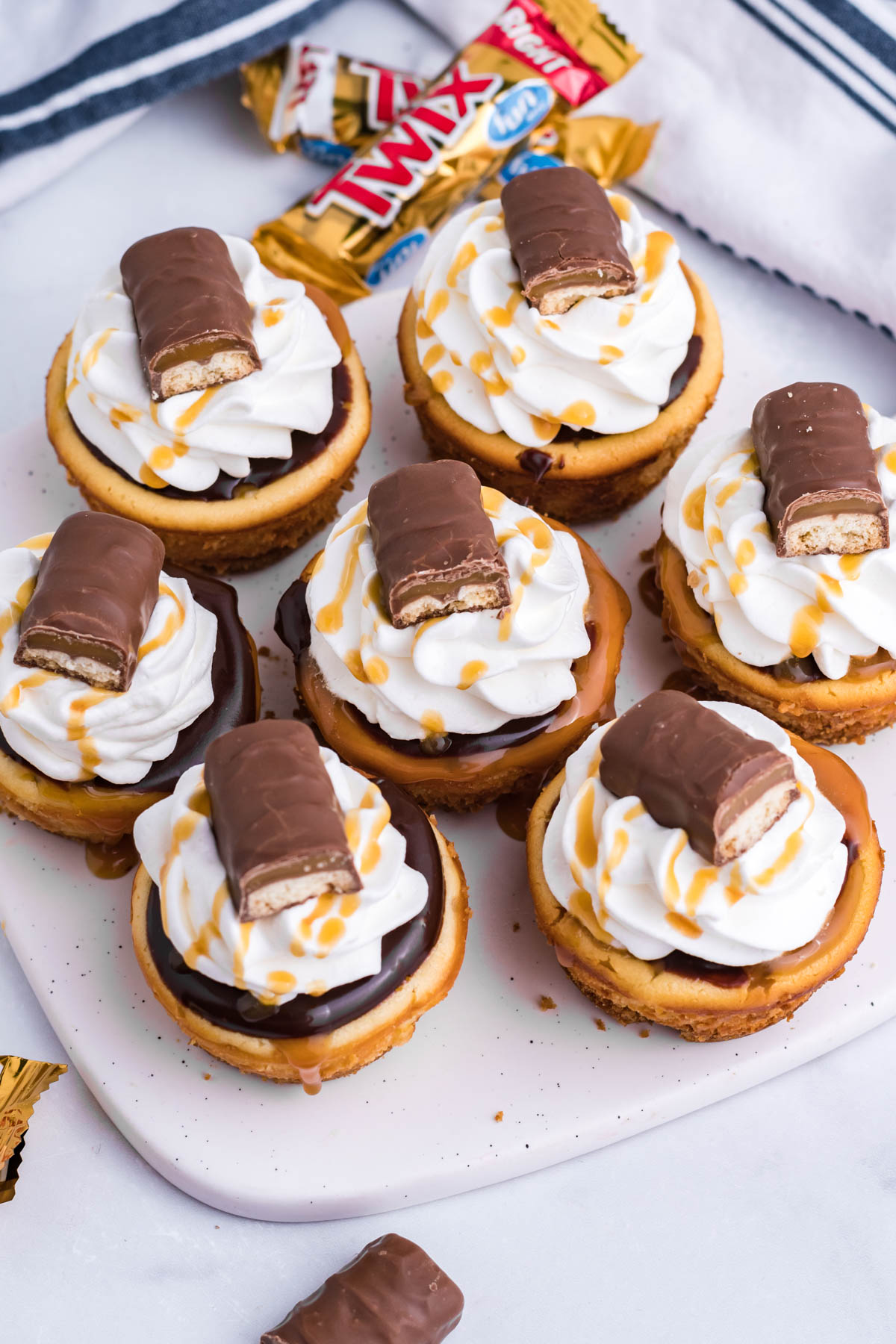Overhead view of the mini Twix cheesecakes on a white marble serving board.