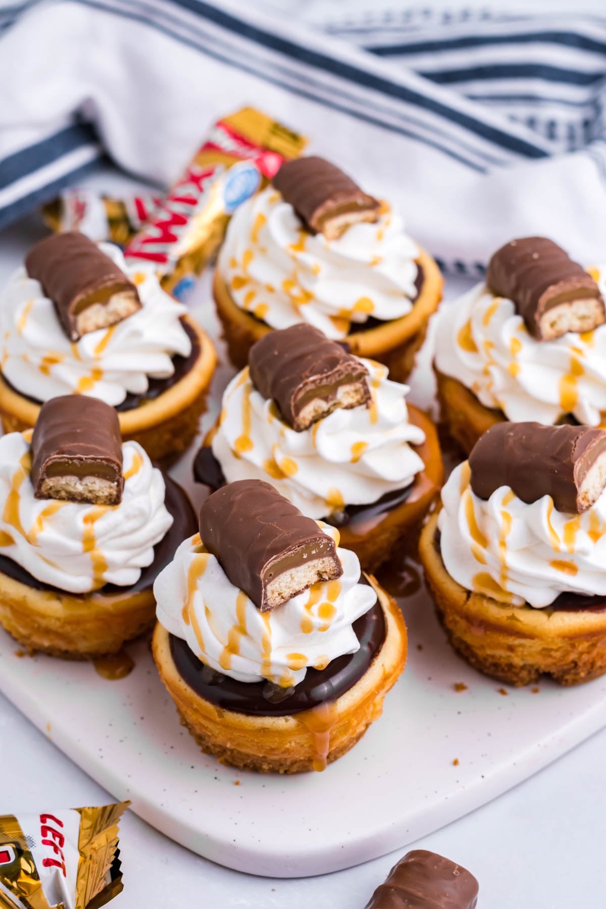 Overhead view of the mini Twix cheesecakes on a white marble serving board.