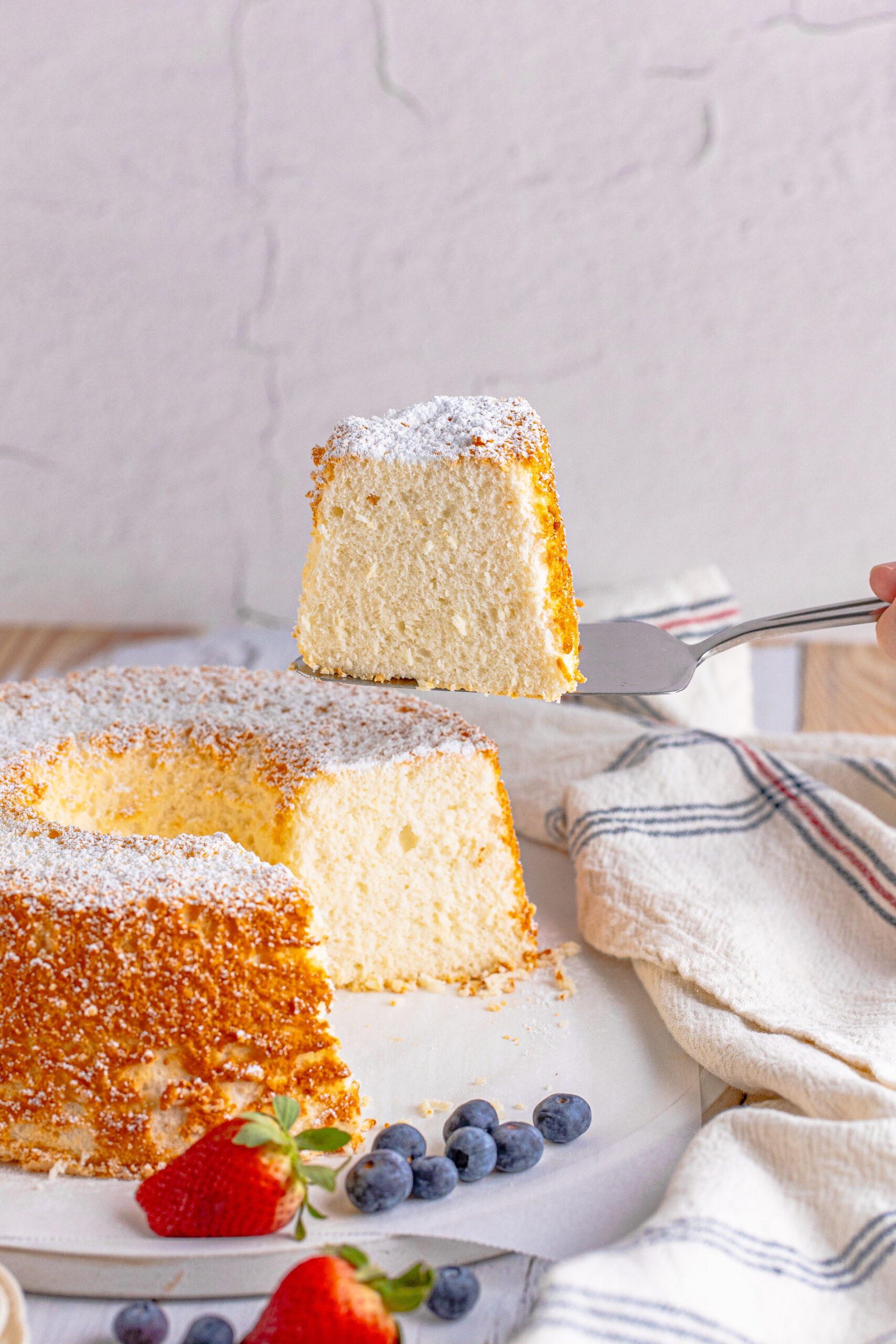 A piece of Angel Food Cake being removed with a silver spatula. 